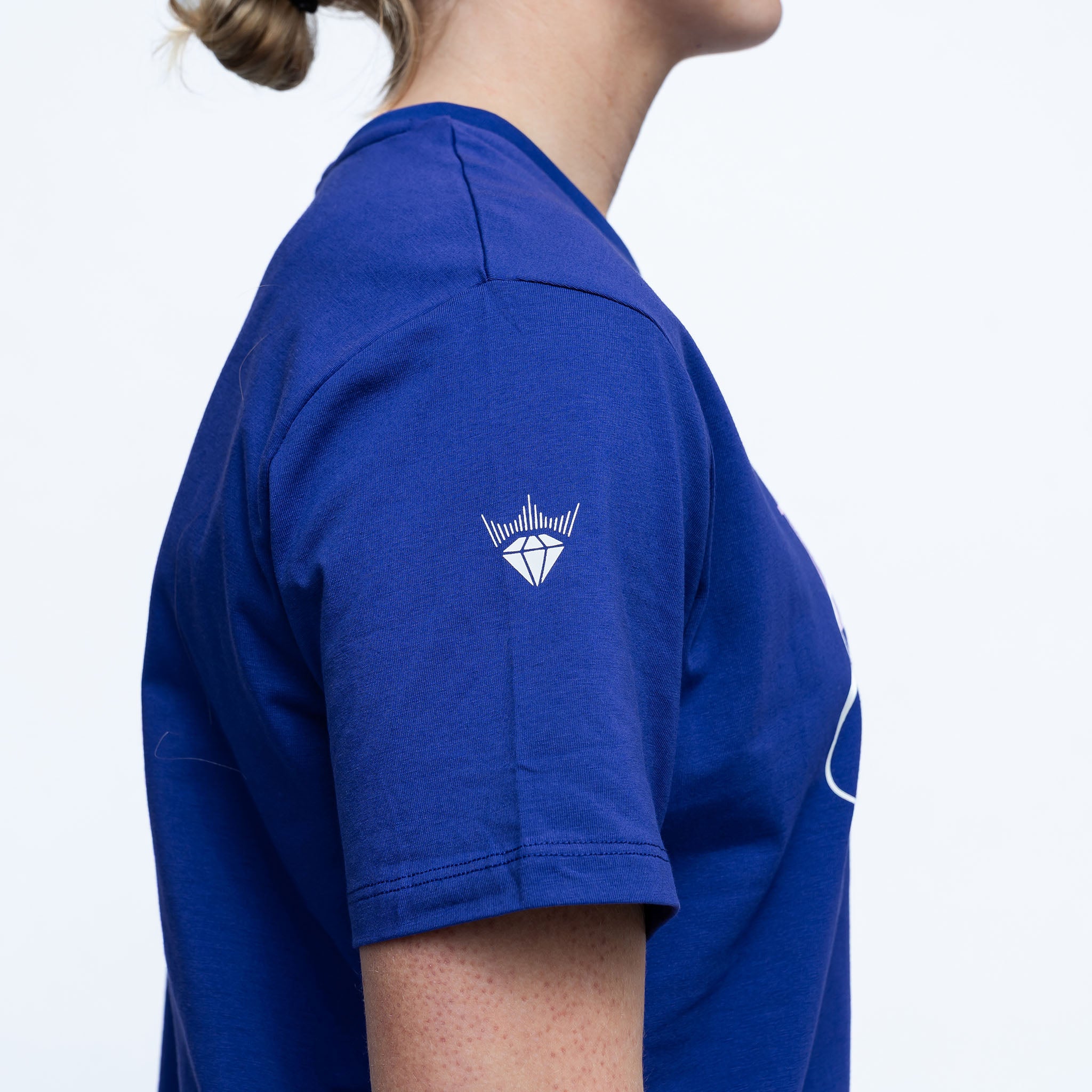 Person wearing a blue shirt with a white logo on a light gray background