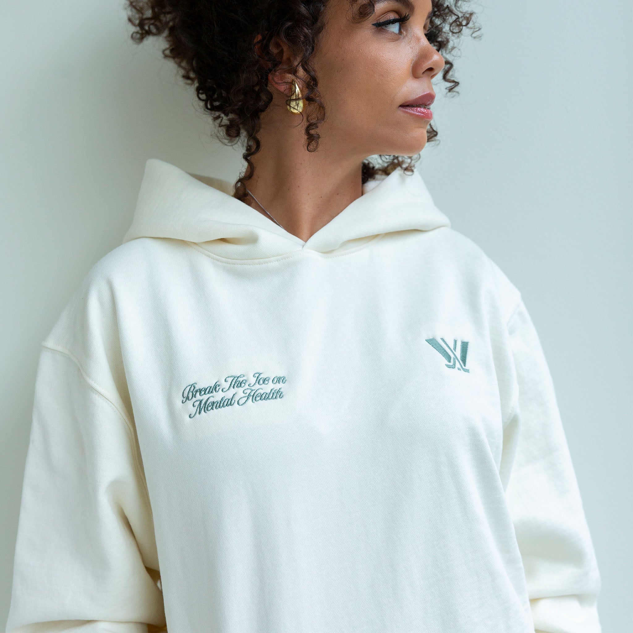 Person wearing a white hoodie with text and logo against a light background