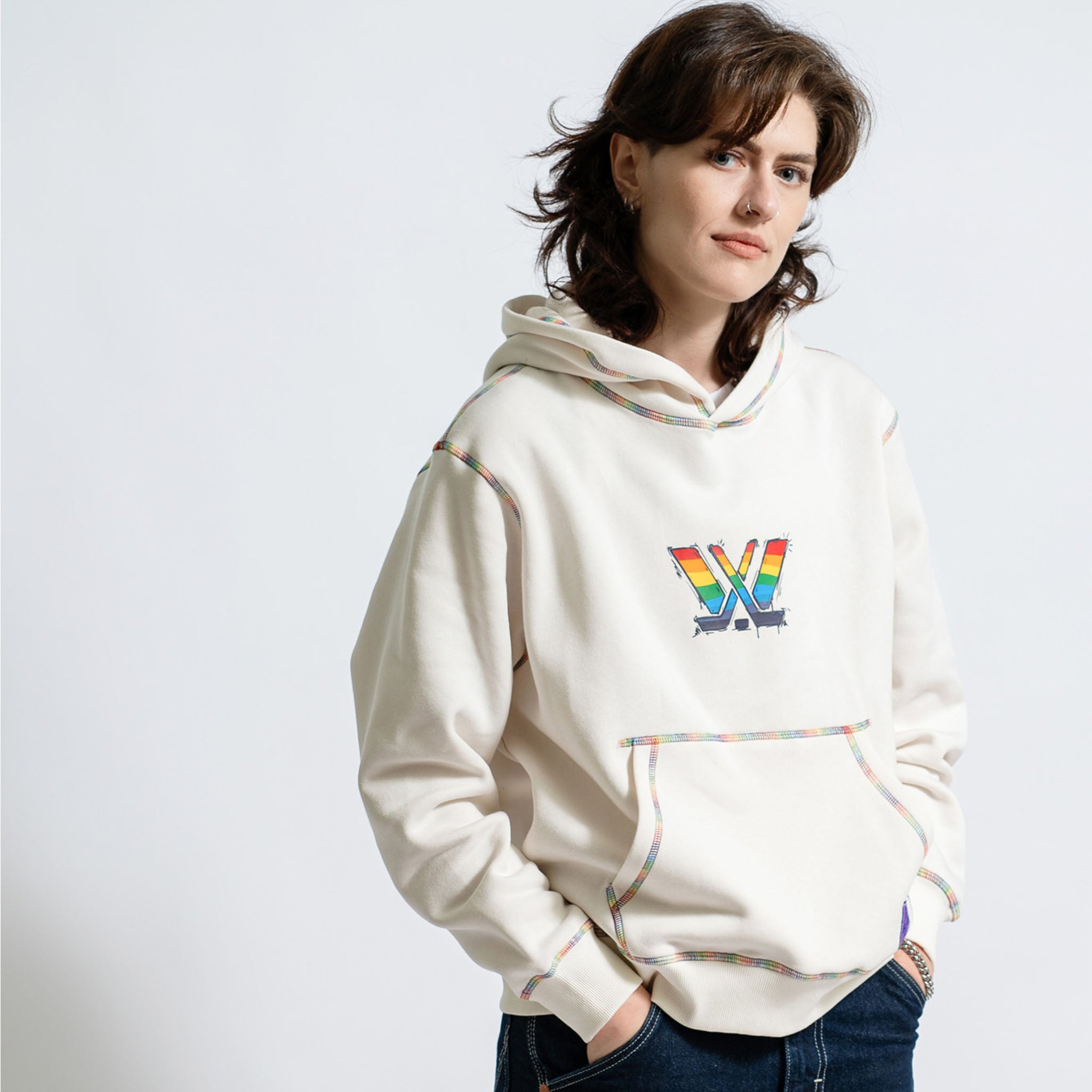 Person wearing a white hoodie with a colorful logo on a light gray background
