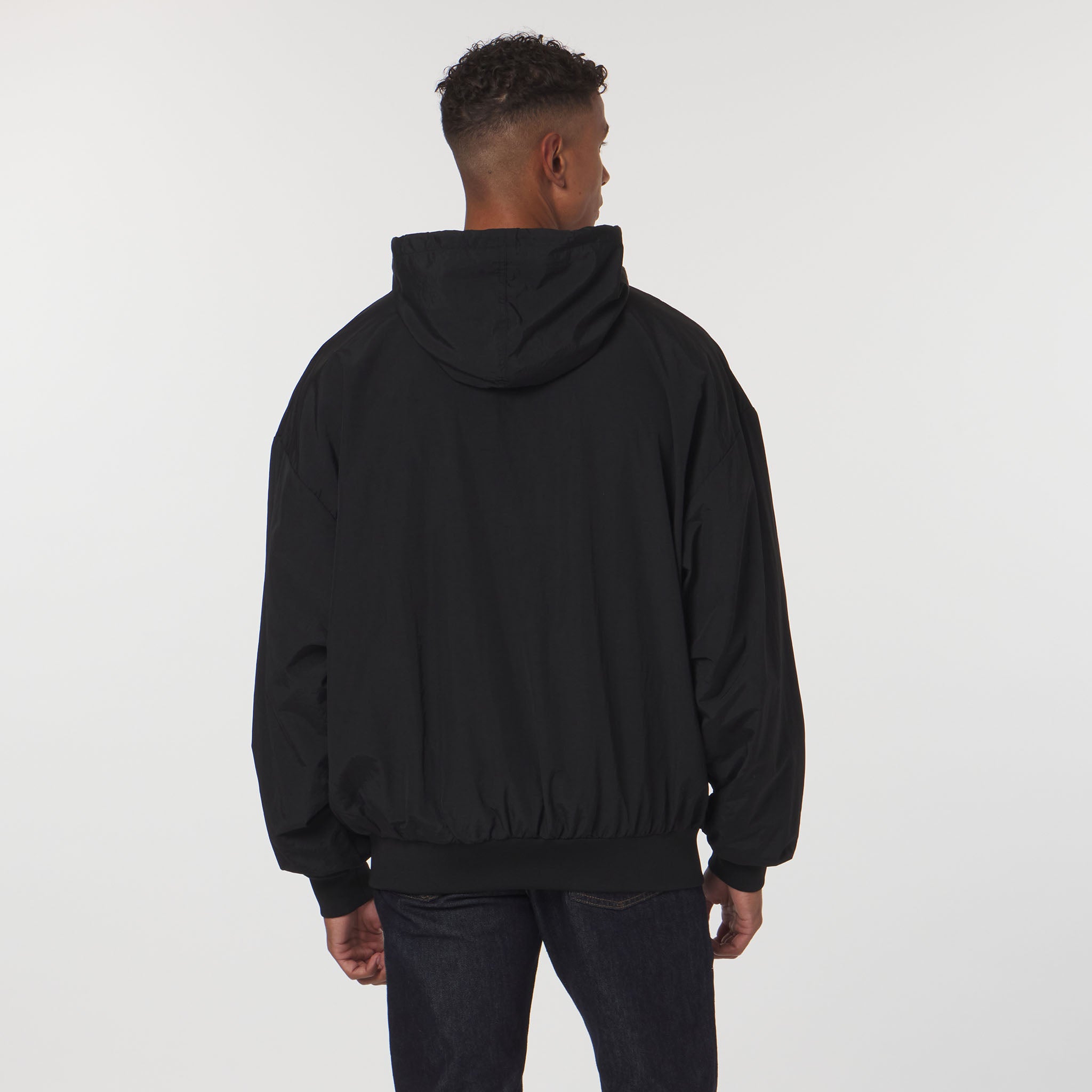 Person wearing a black hoodie from behind on a white background