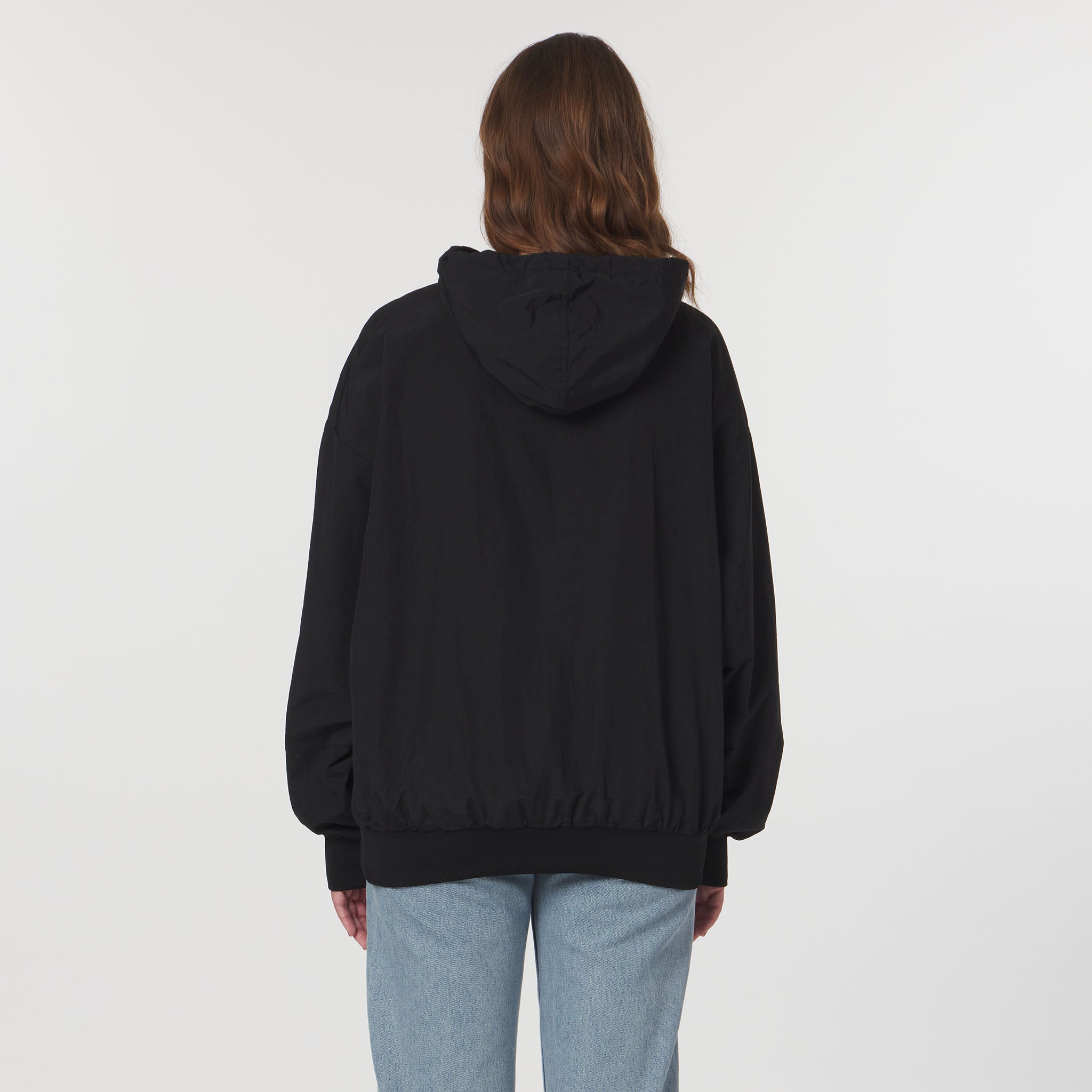 Person wearing a black hoodie from behind on a light gray background