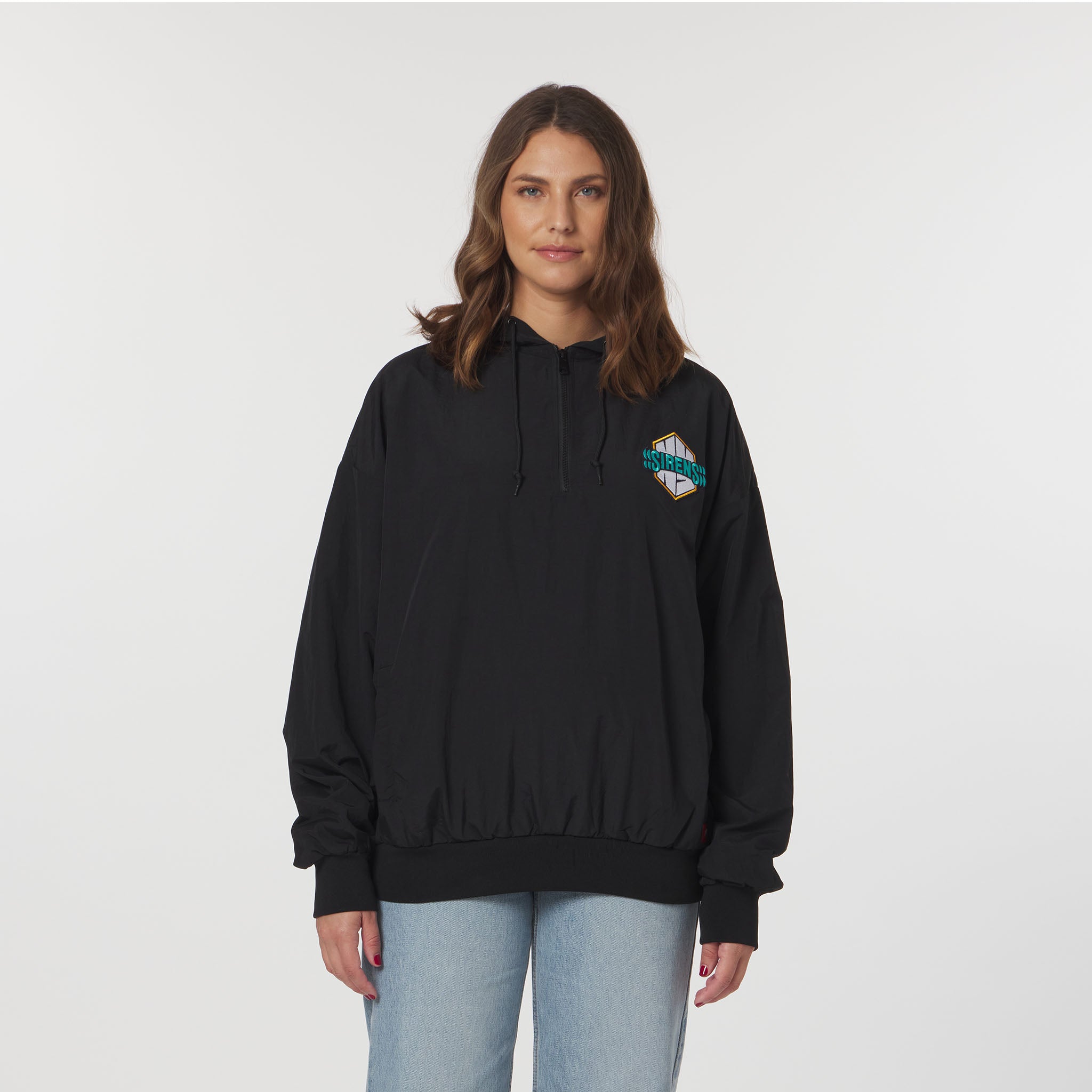 Person wearing a black hoodie with a logo on the chest against a plain background