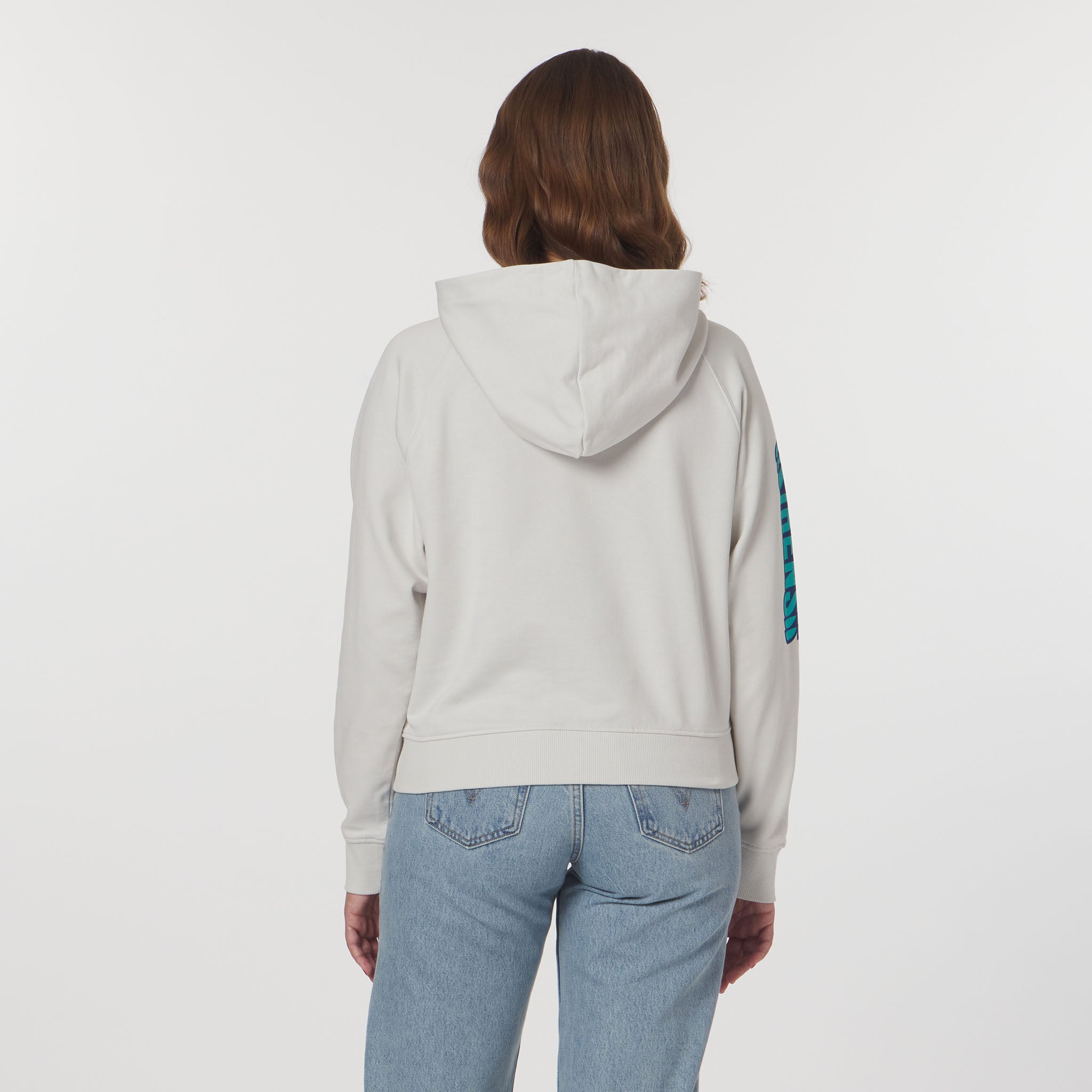 Person wearing a light gray hoodie with a blue design on the sleeve against a white background