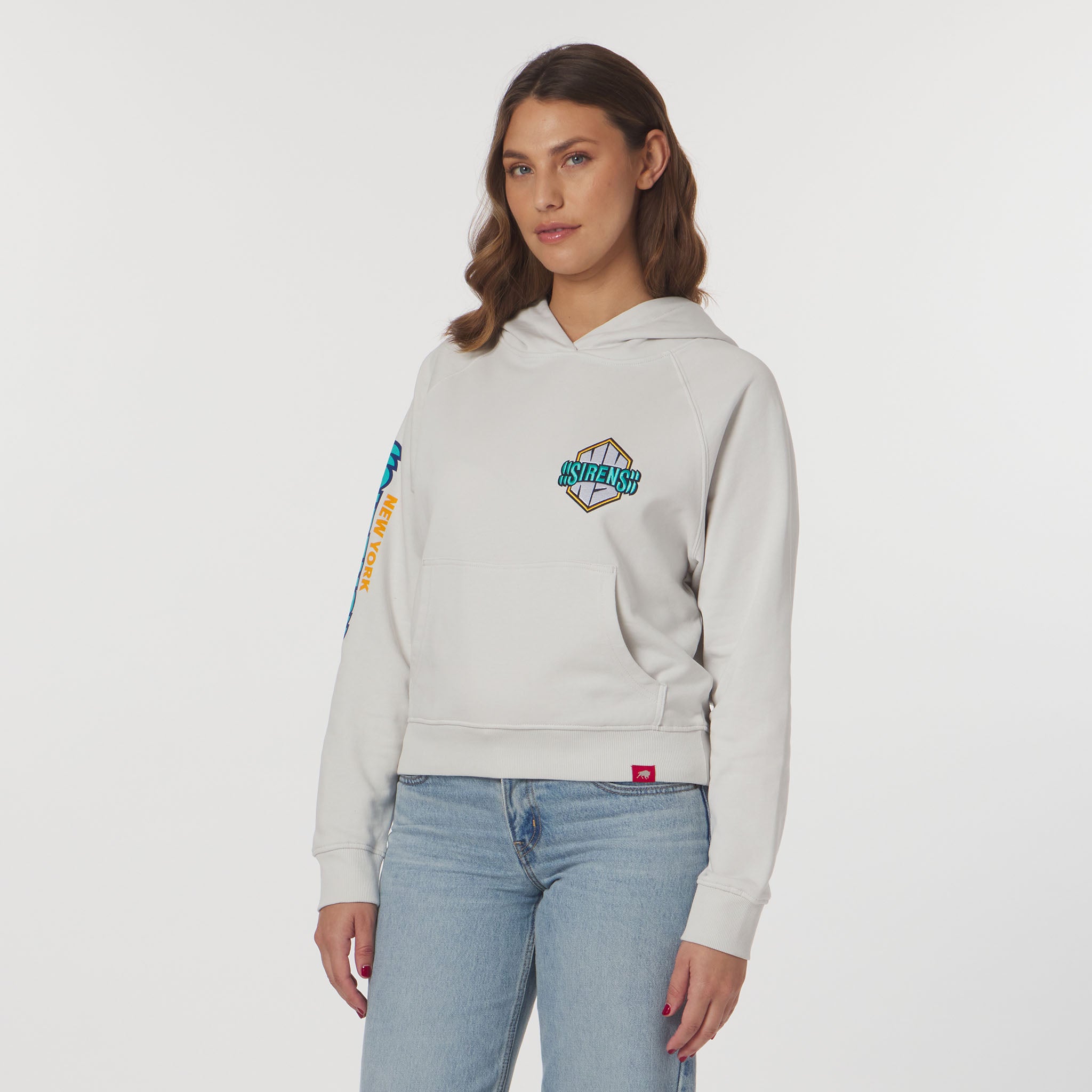 Woman wearing a light gray hoodie with branding on a white background