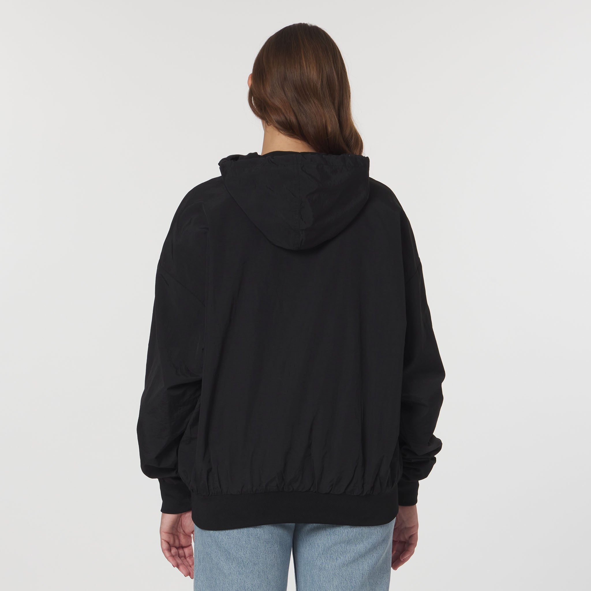 Person wearing a black hoodie from behind on a light gray background