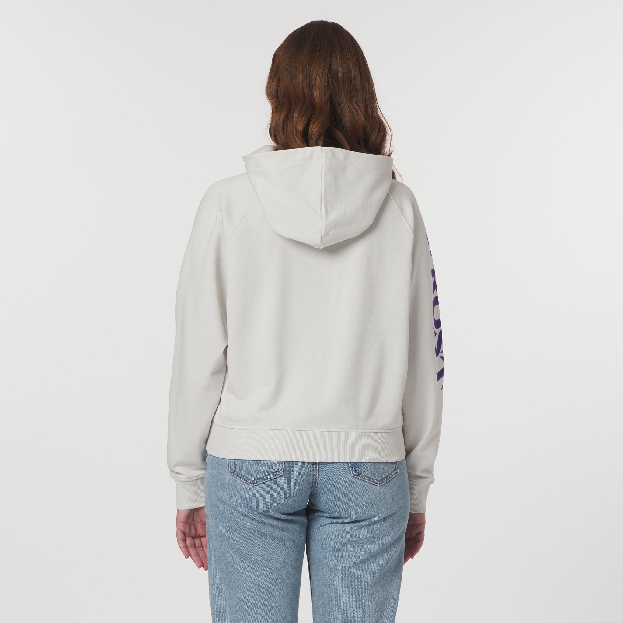 Person wearing a light gray hoodie with a colorful design on the sleeve against a white background