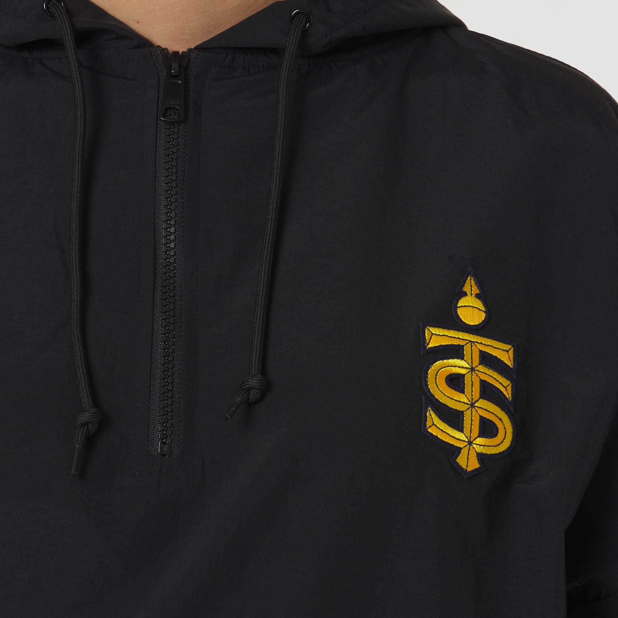 Black hoodie with a yellow logo on the chest against a gray background