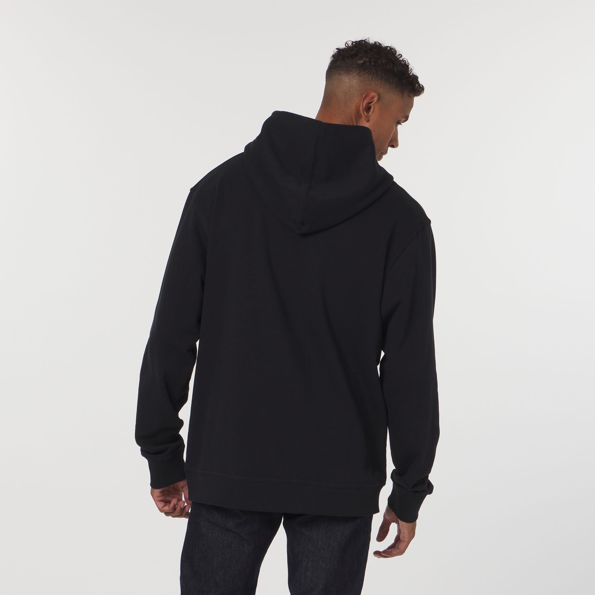 Person wearing a black hoodie from behind on a white background