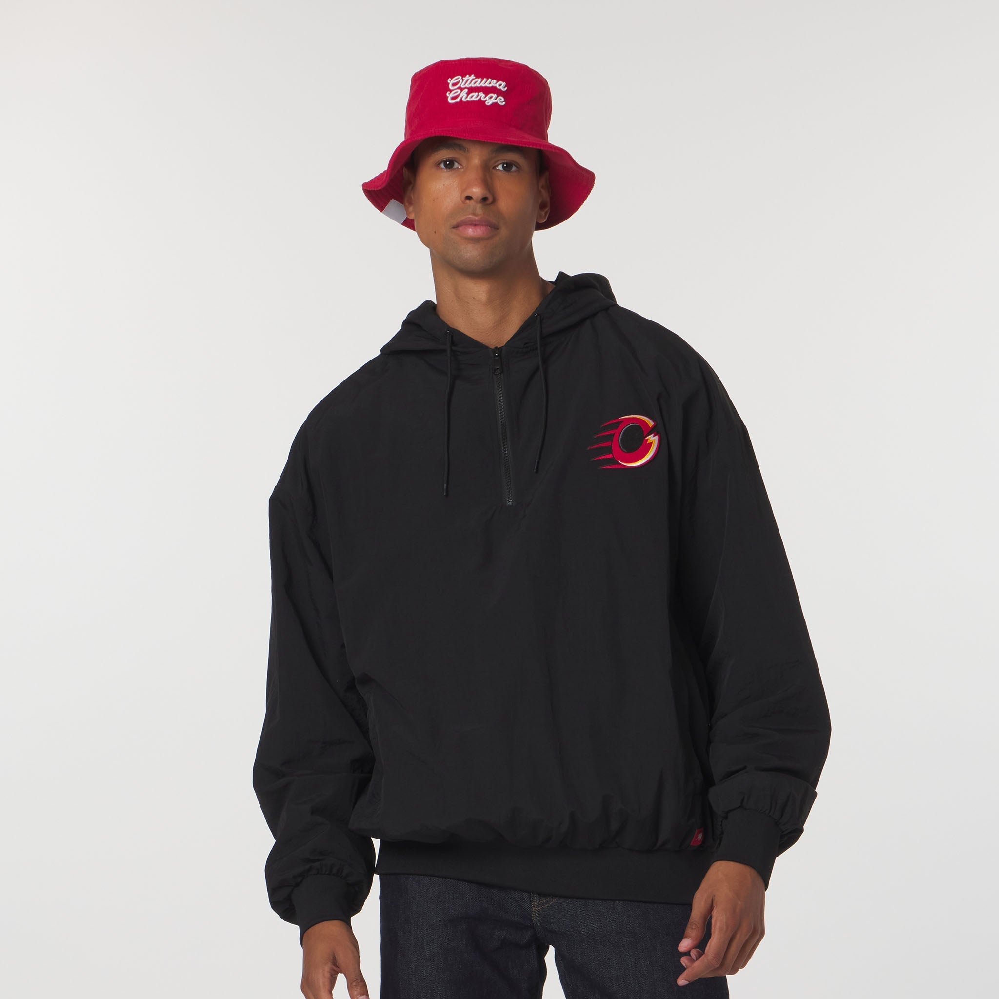 Person wearing a black hoodie with a red logo and a red bucket hat on a white background