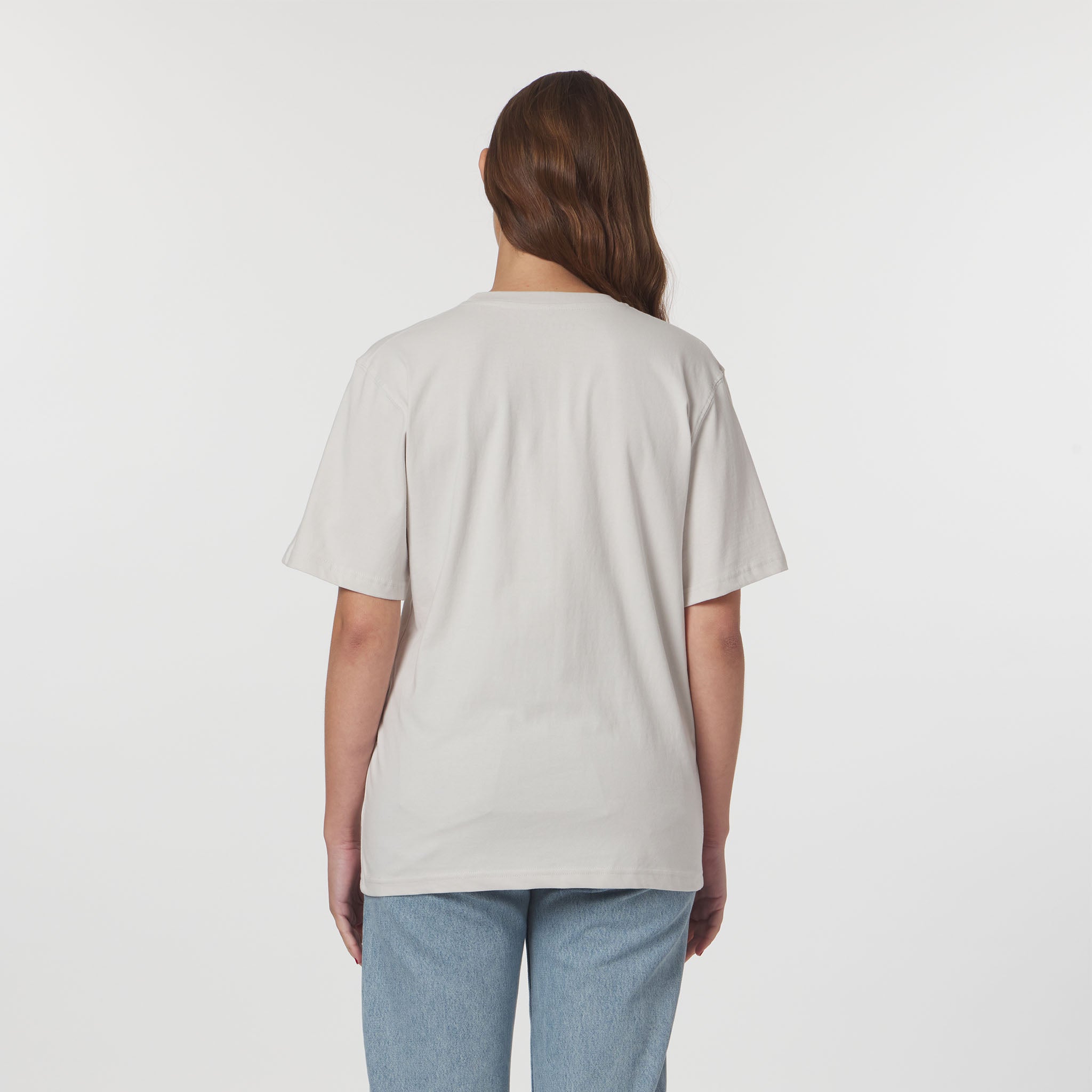 Person wearing a beige t-shirt and light blue jeans on a white background