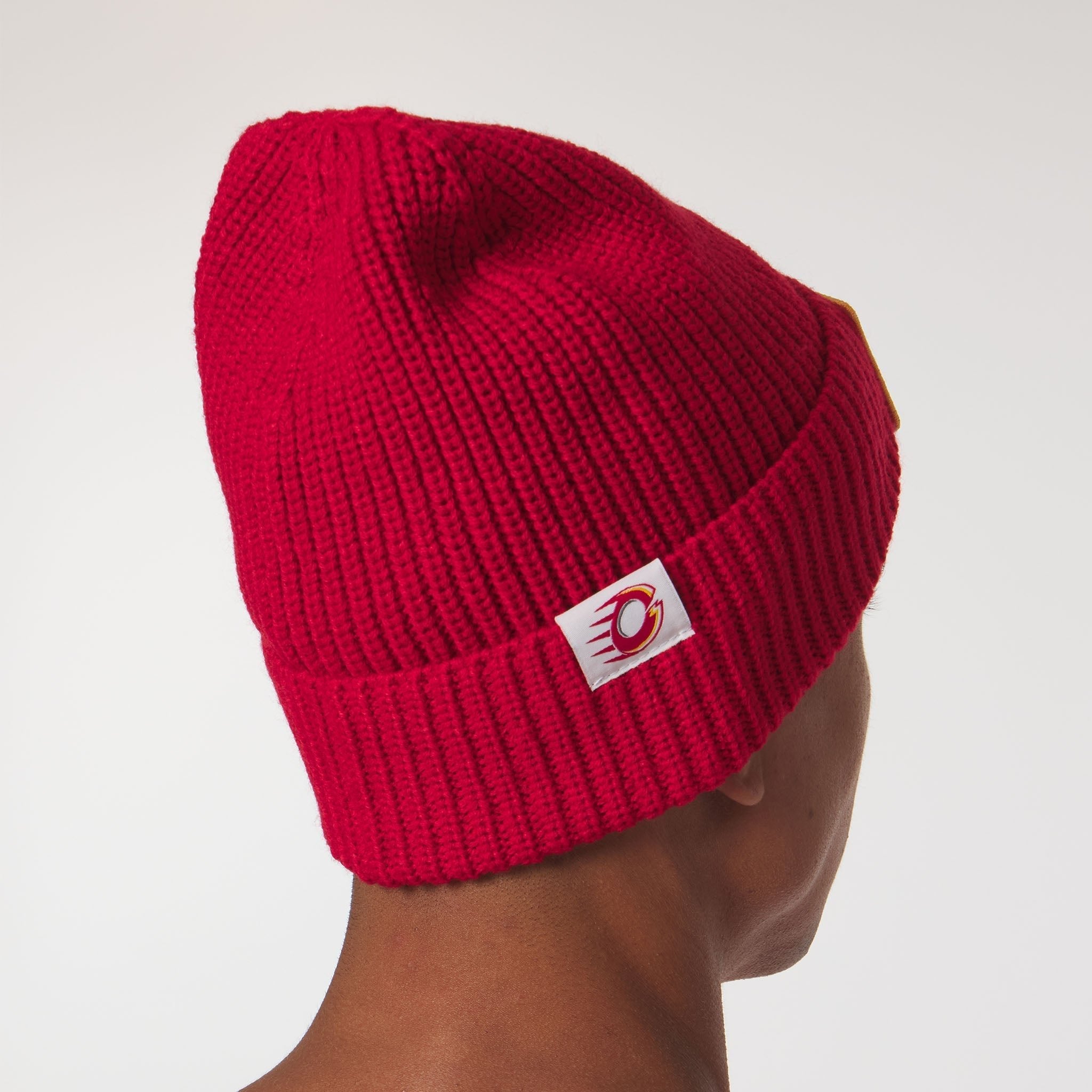 Red knit beanie with a logo on a neutral background