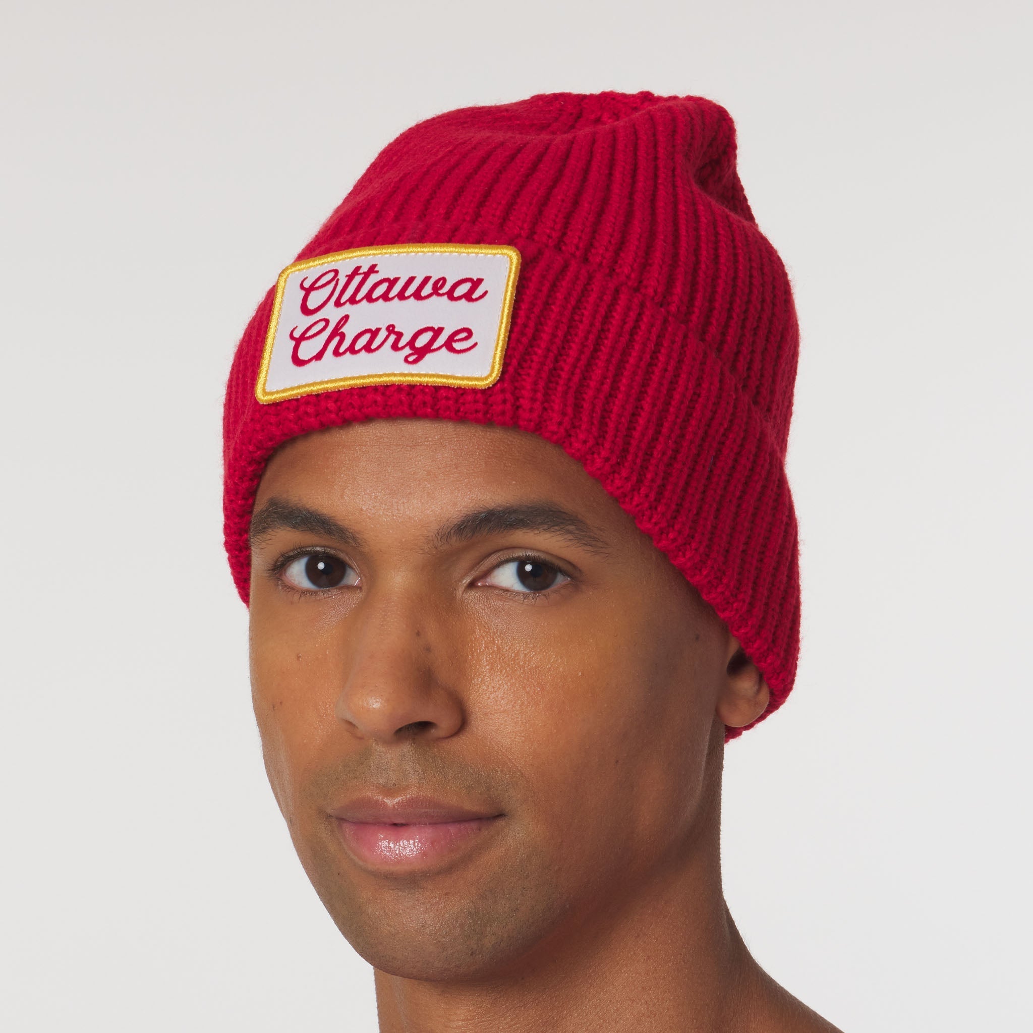 Person wearing a red beanie with 'Ottawa Charge' patch on a white background
