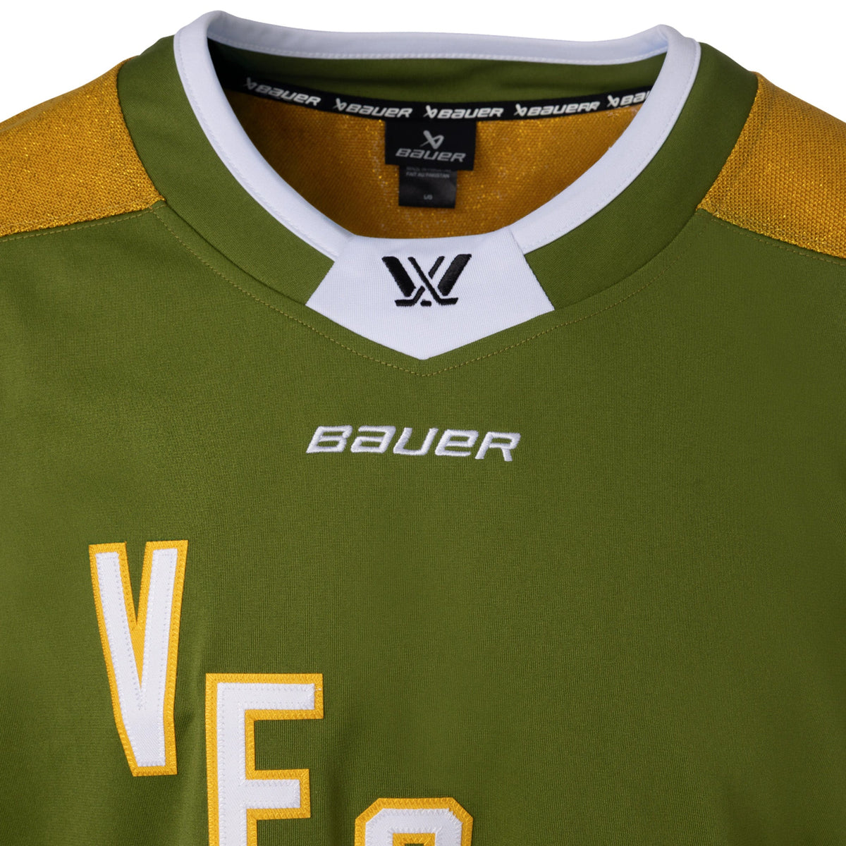 Front of a green jersey with sparkling gold shoulder caps and stripes along the sleeves surrounded by white and black stripes. In white outlined in gold reads 'VEGAS' diagonally across the chest. The collar is green with white trim on top. A black PWHL logo is centered on the collar with a white BAUER logo below it.
