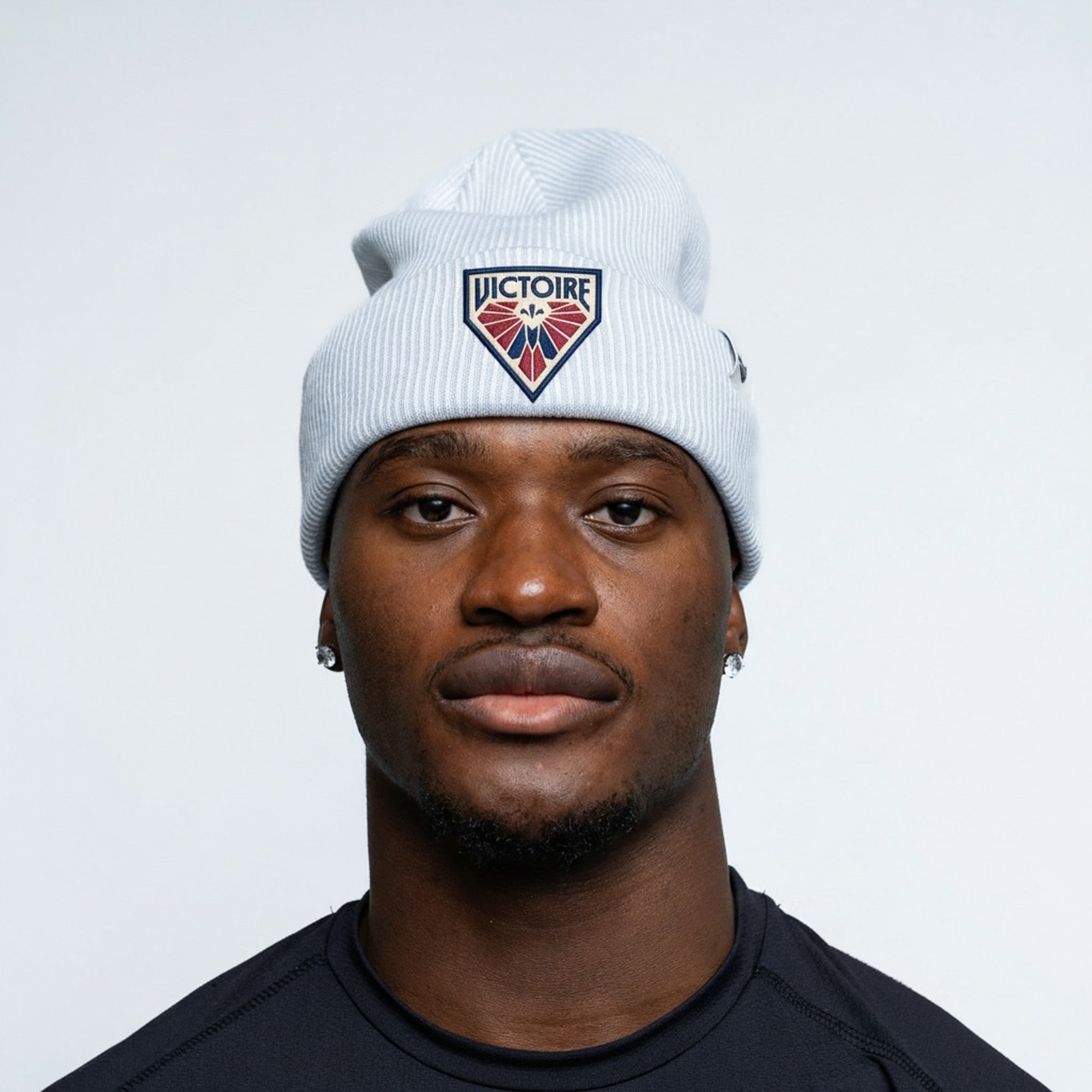 Man wearing a white beanie with a logo on a light gray background