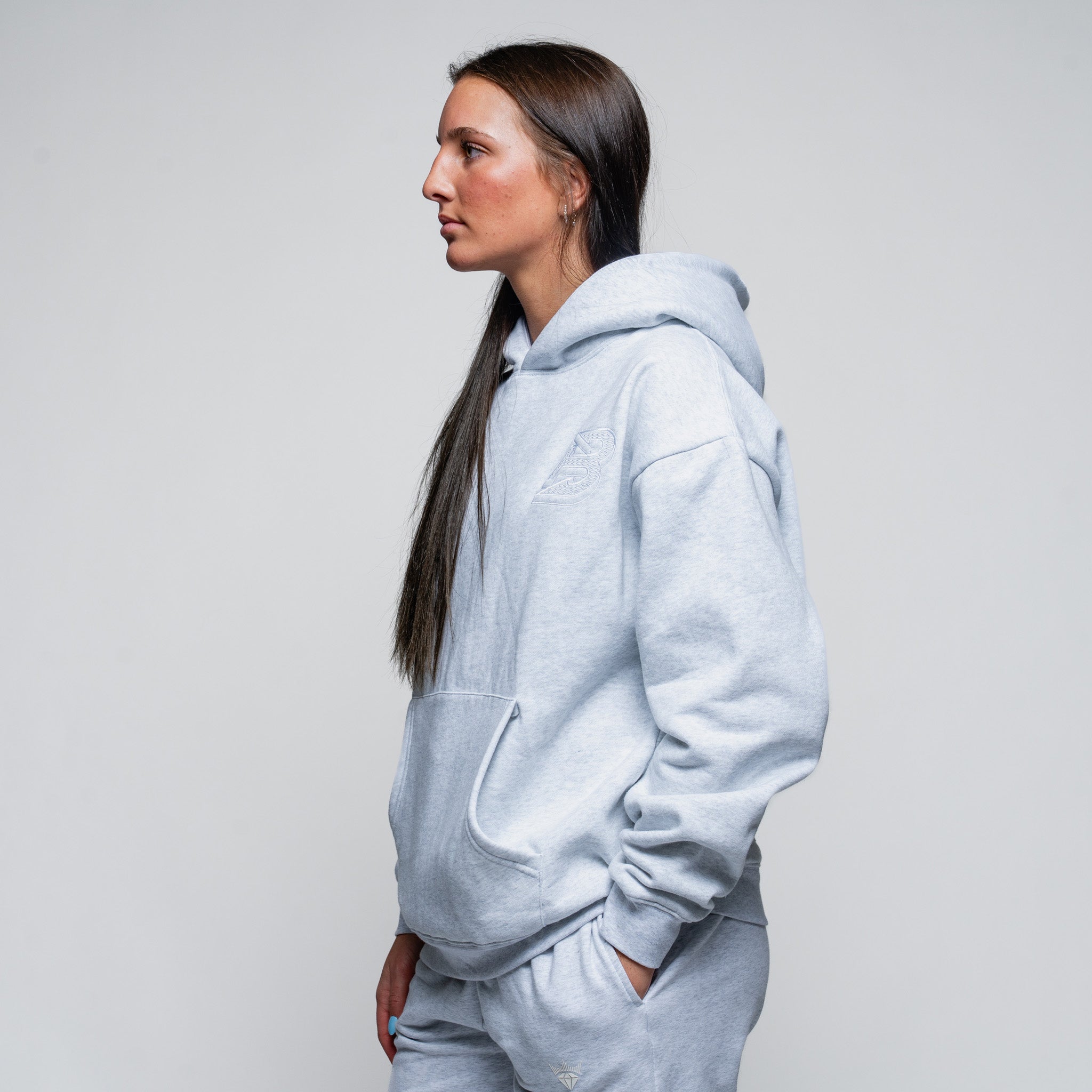 Person wearing a light gray hoodie and pants on a plain background