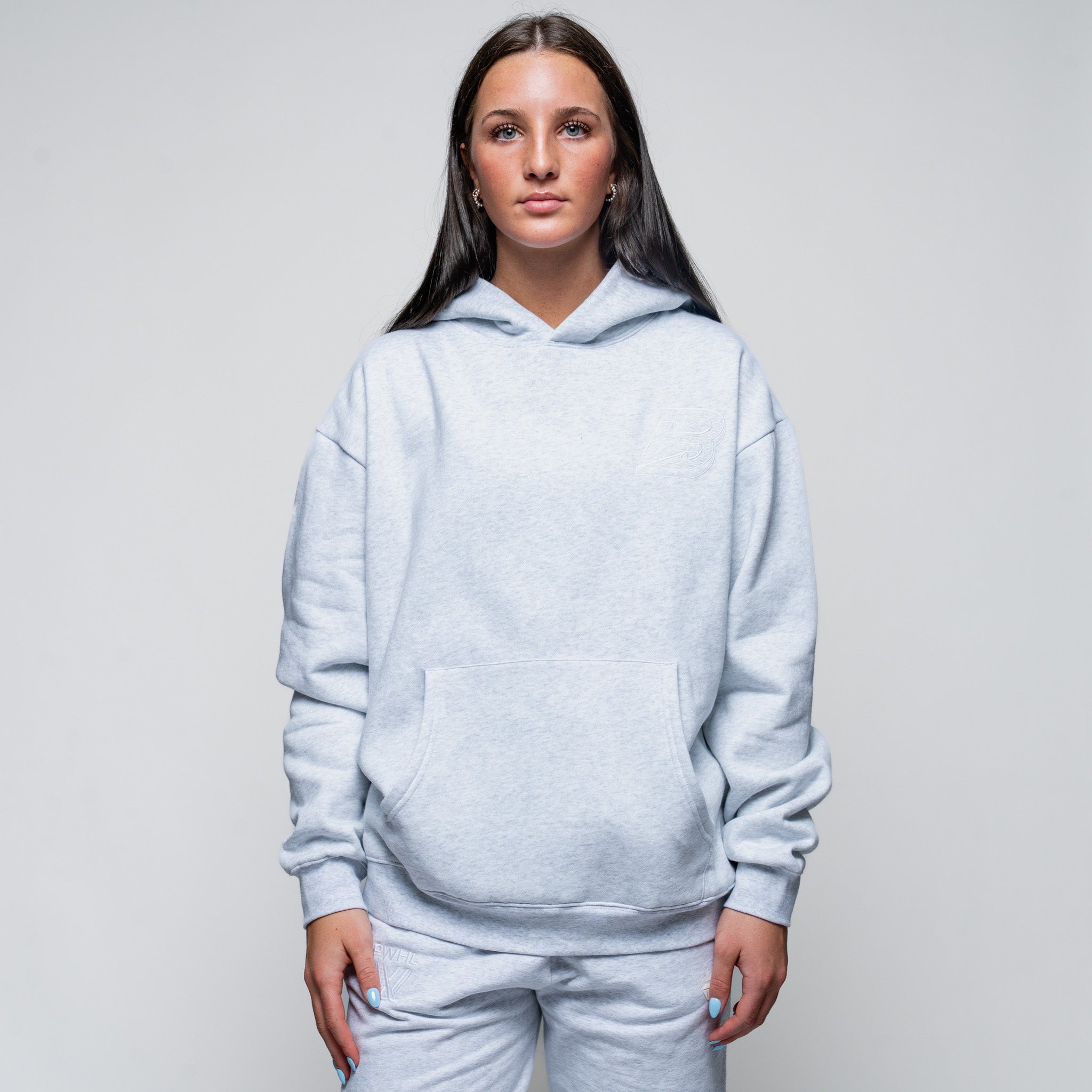 Person wearing a light gray hoodie and pants on a plain background