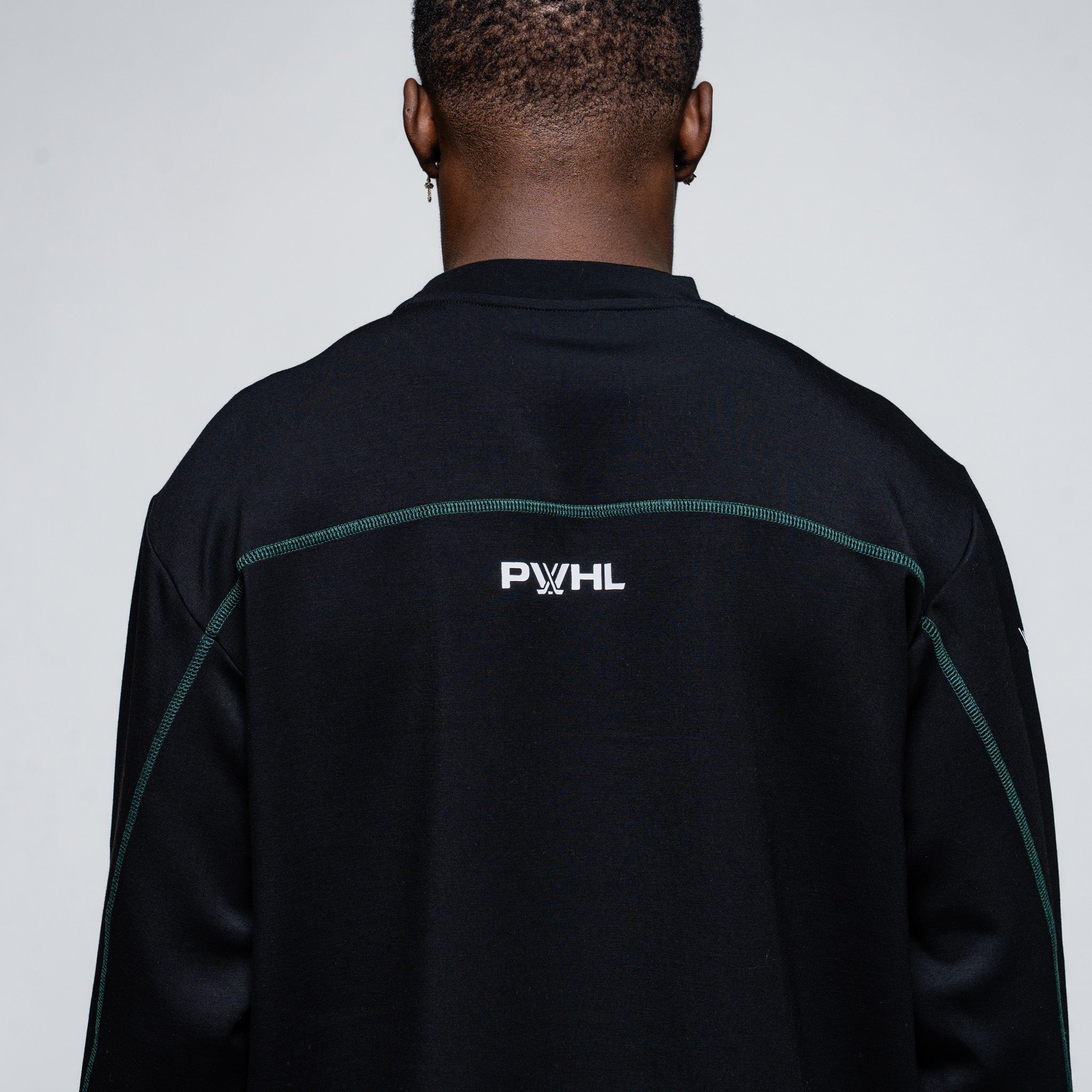 Person wearing a black jacket with 'PWHL' logo on the back against a gray background