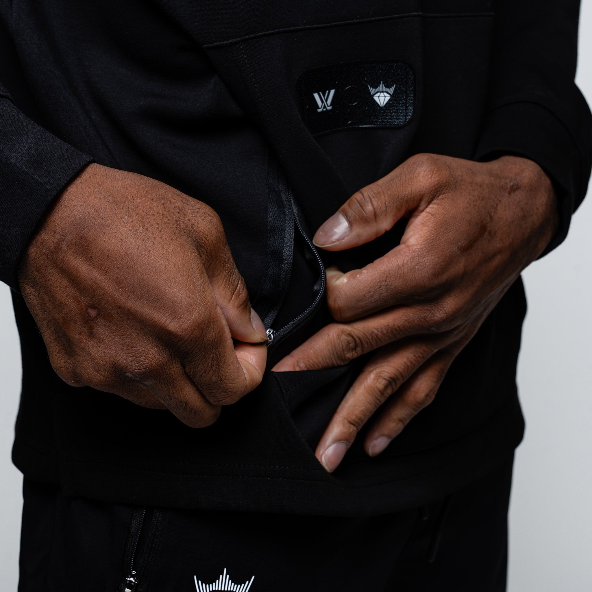 Person wearing a black hoodie with a brand logo on a gray background