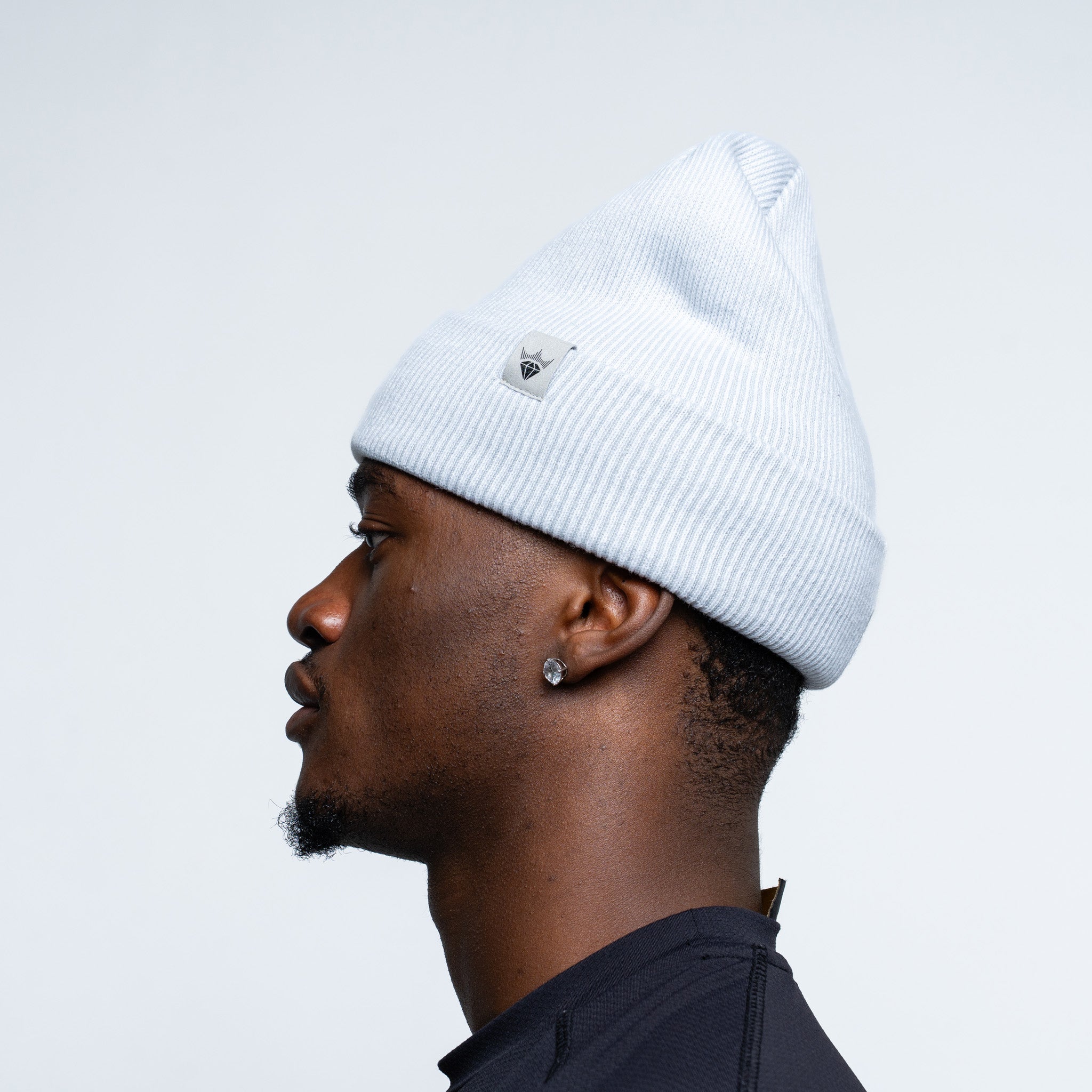 Person wearing a white beanie against a light gray background