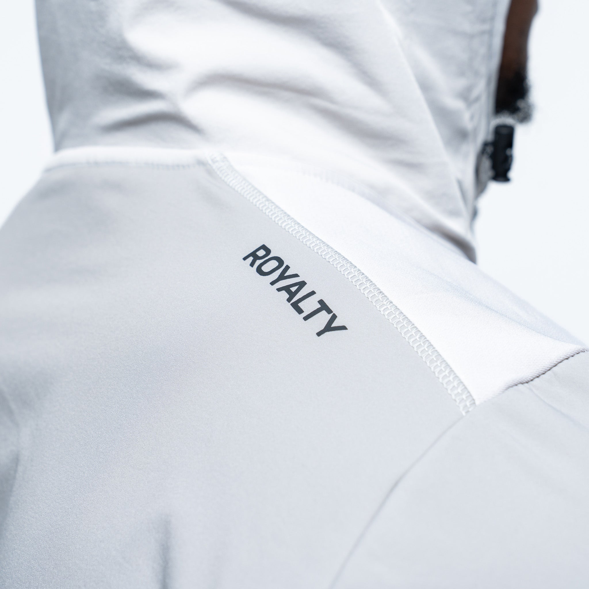 White and grey jacket with 'ROYALTY' text on a blurred background