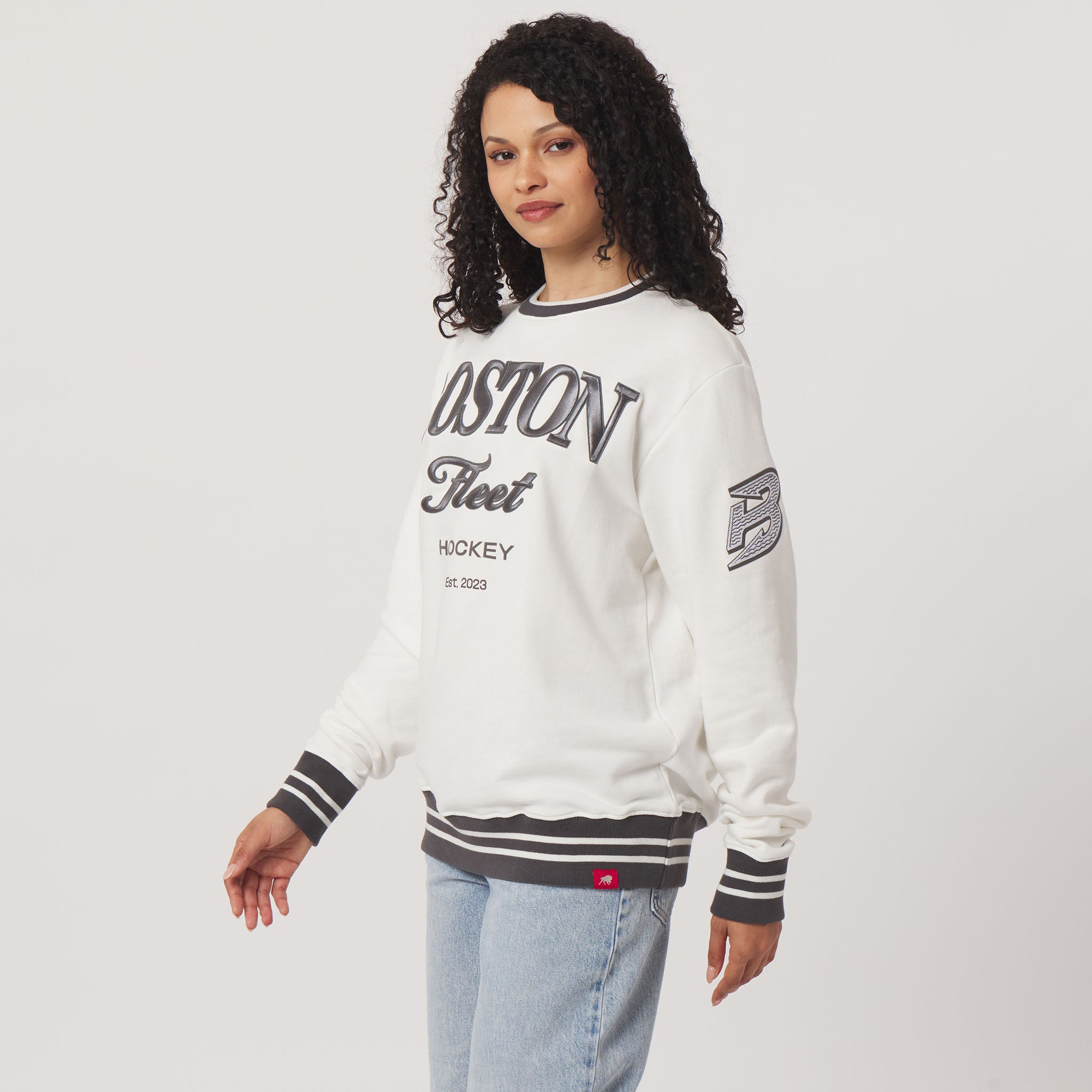 Woman wearing a white sweatshirt with text and logos on a plain background