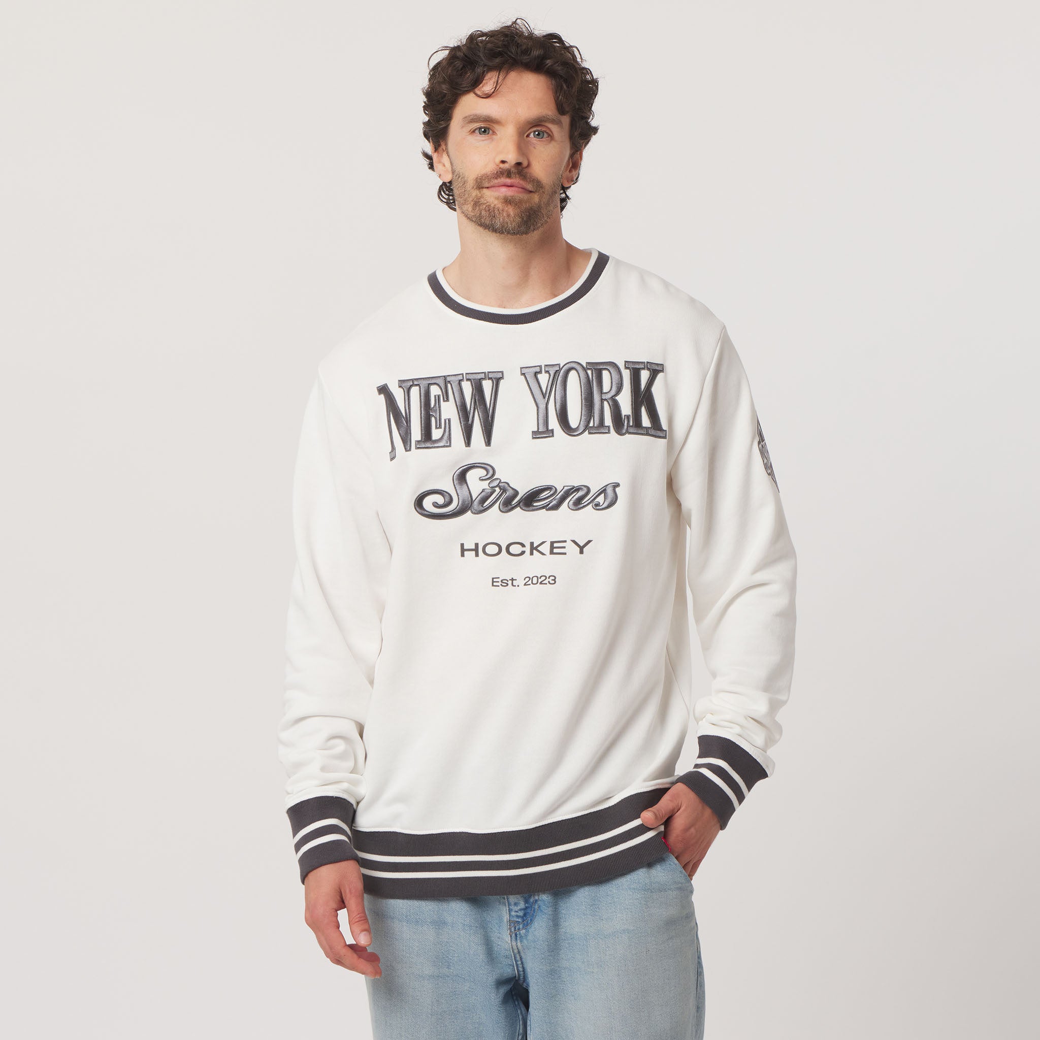 Man wearing a white sweatshirt with 'New York Strens Hockey' text on a plain background