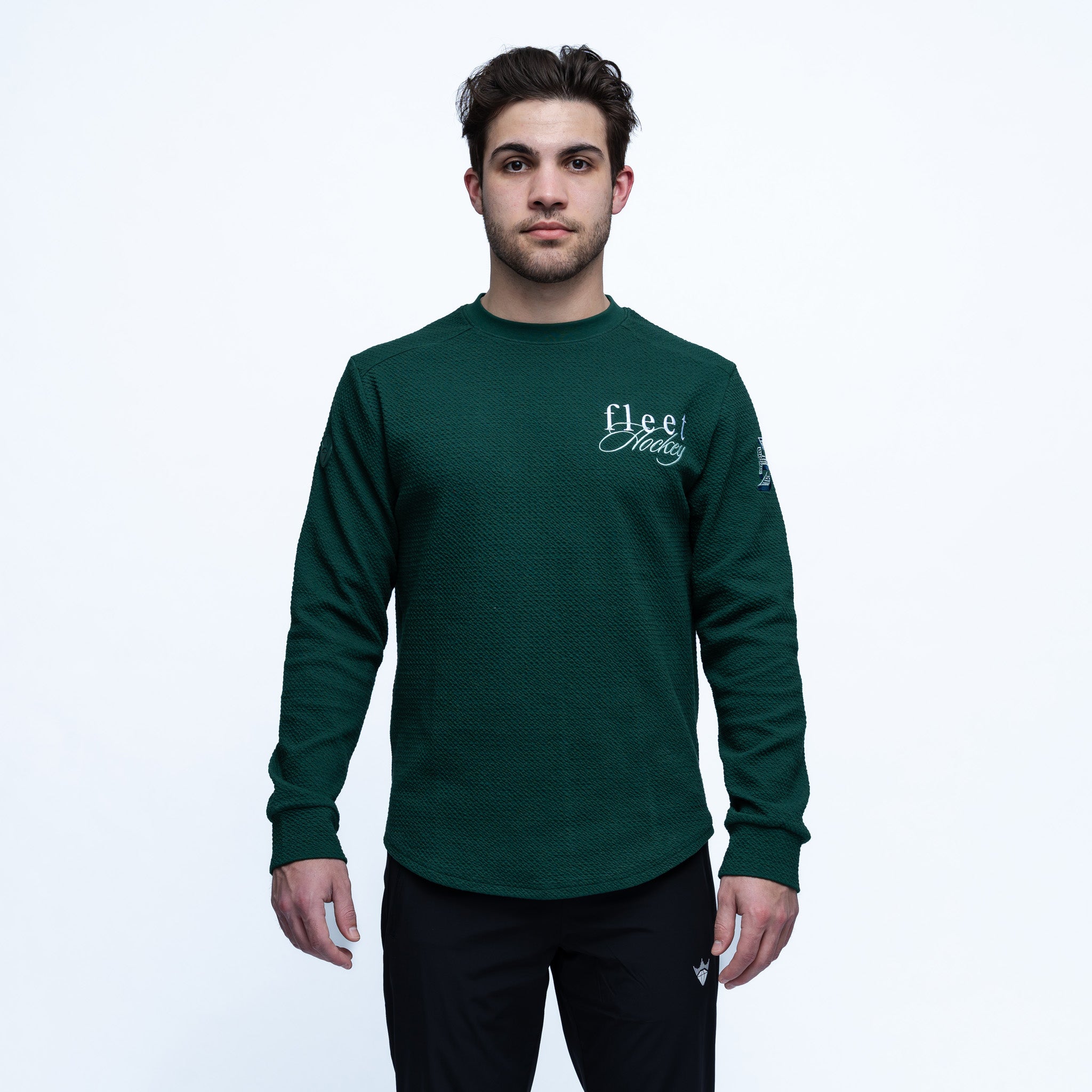 Man wearing a green long-sleeve shirt with a logo on a white background