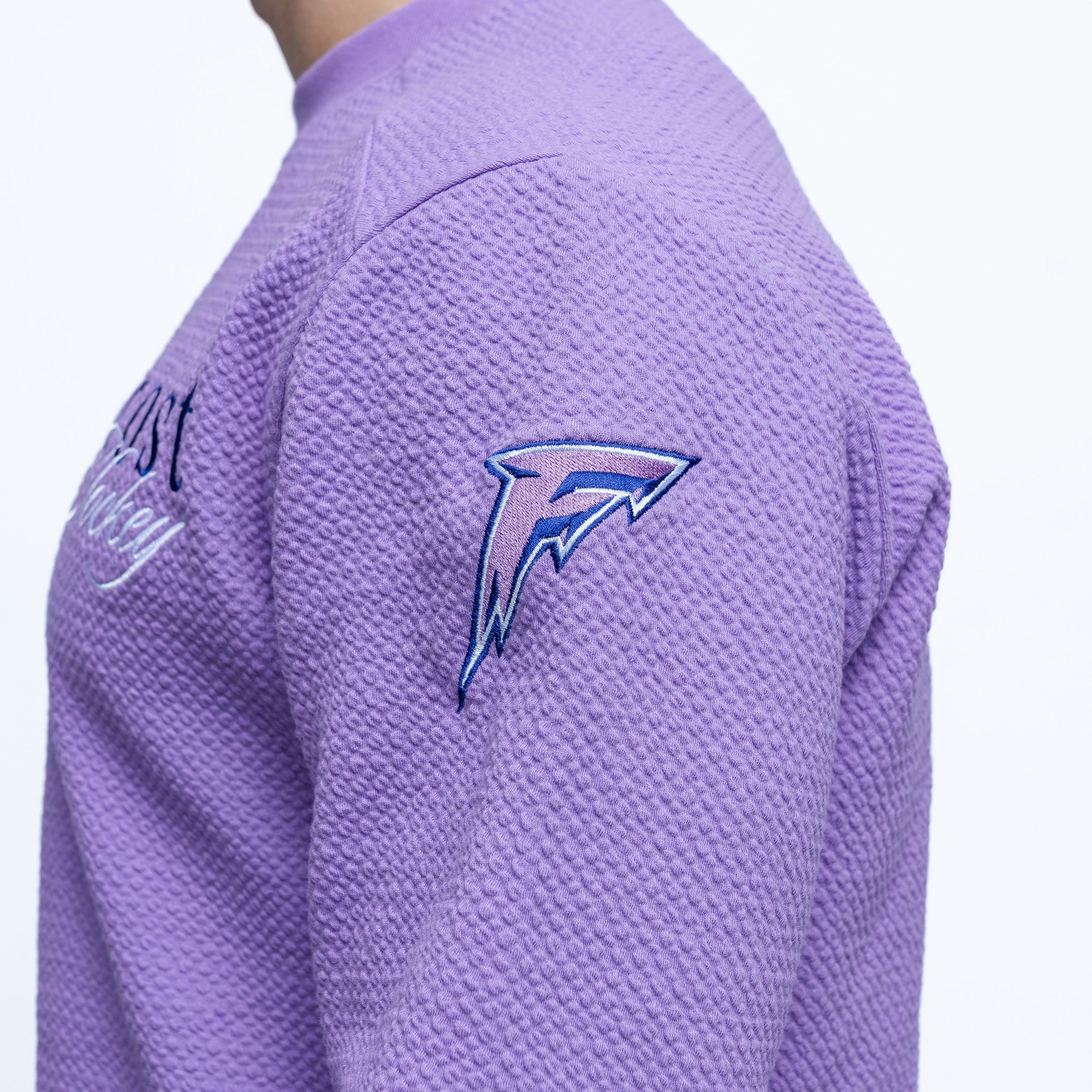 Purple shirt with a logo on the sleeve against a white background