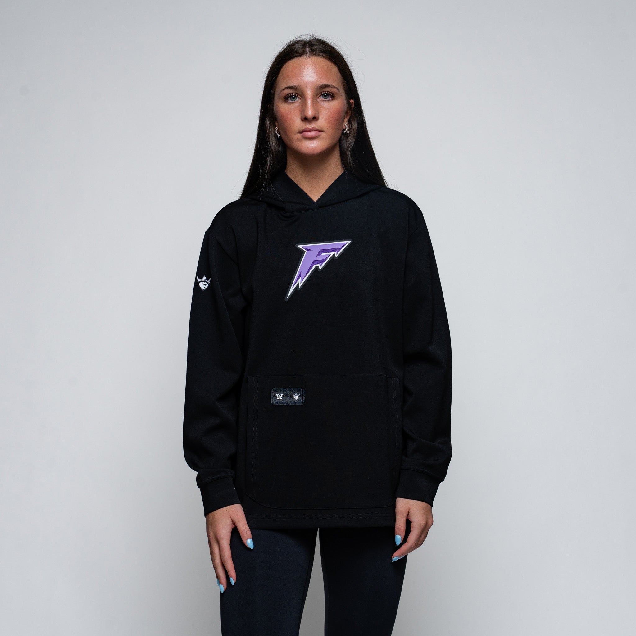 Person wearing a black hoodie with a purple logo on a plain background