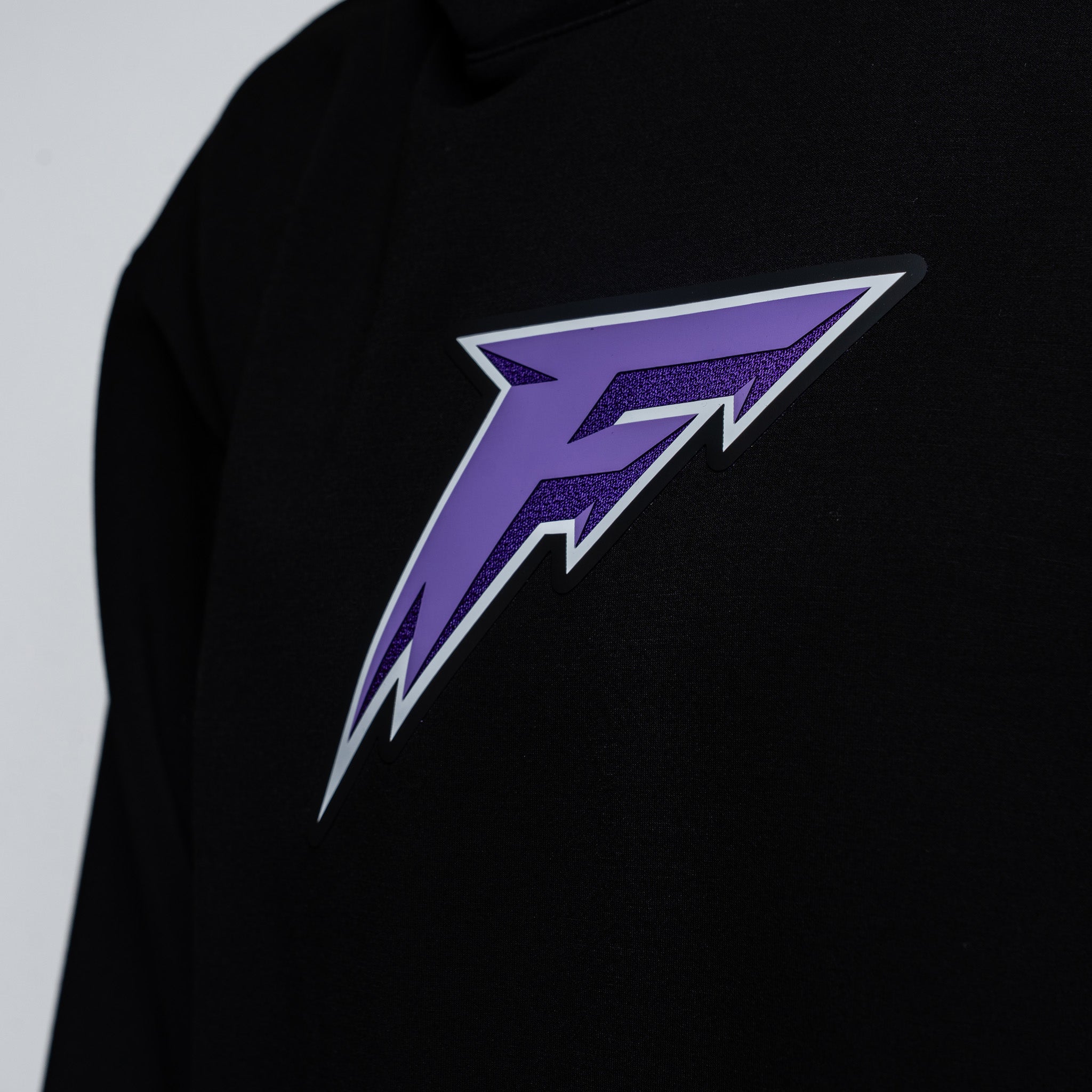 Black hoodie with a purple and white logo on a light gray background