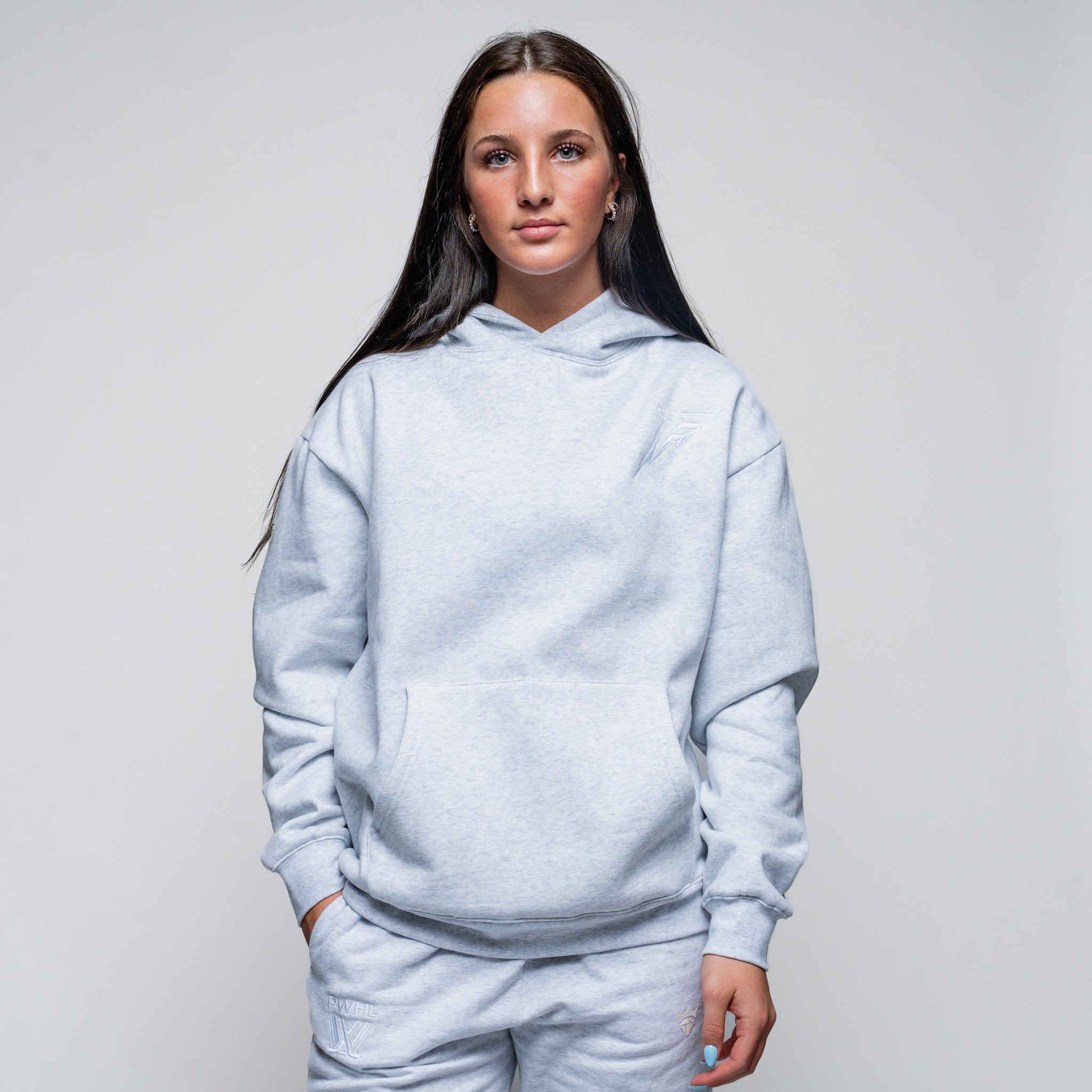 Person wearing a light gray hoodie and pants on a plain background