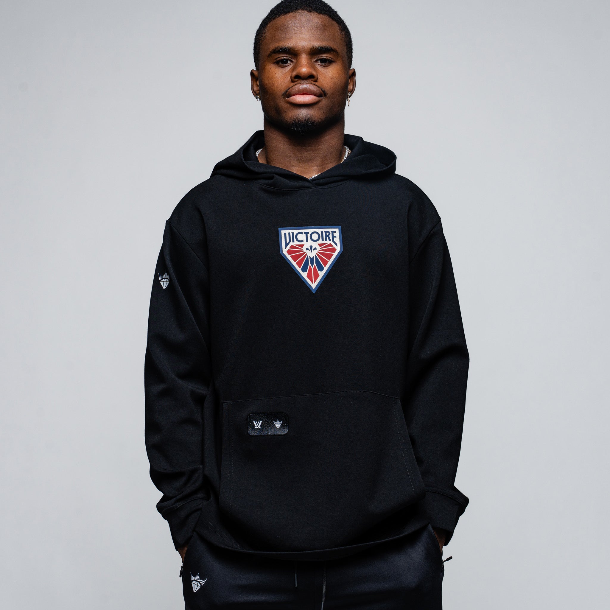Person wearing a black hoodie with a logo on a gray background