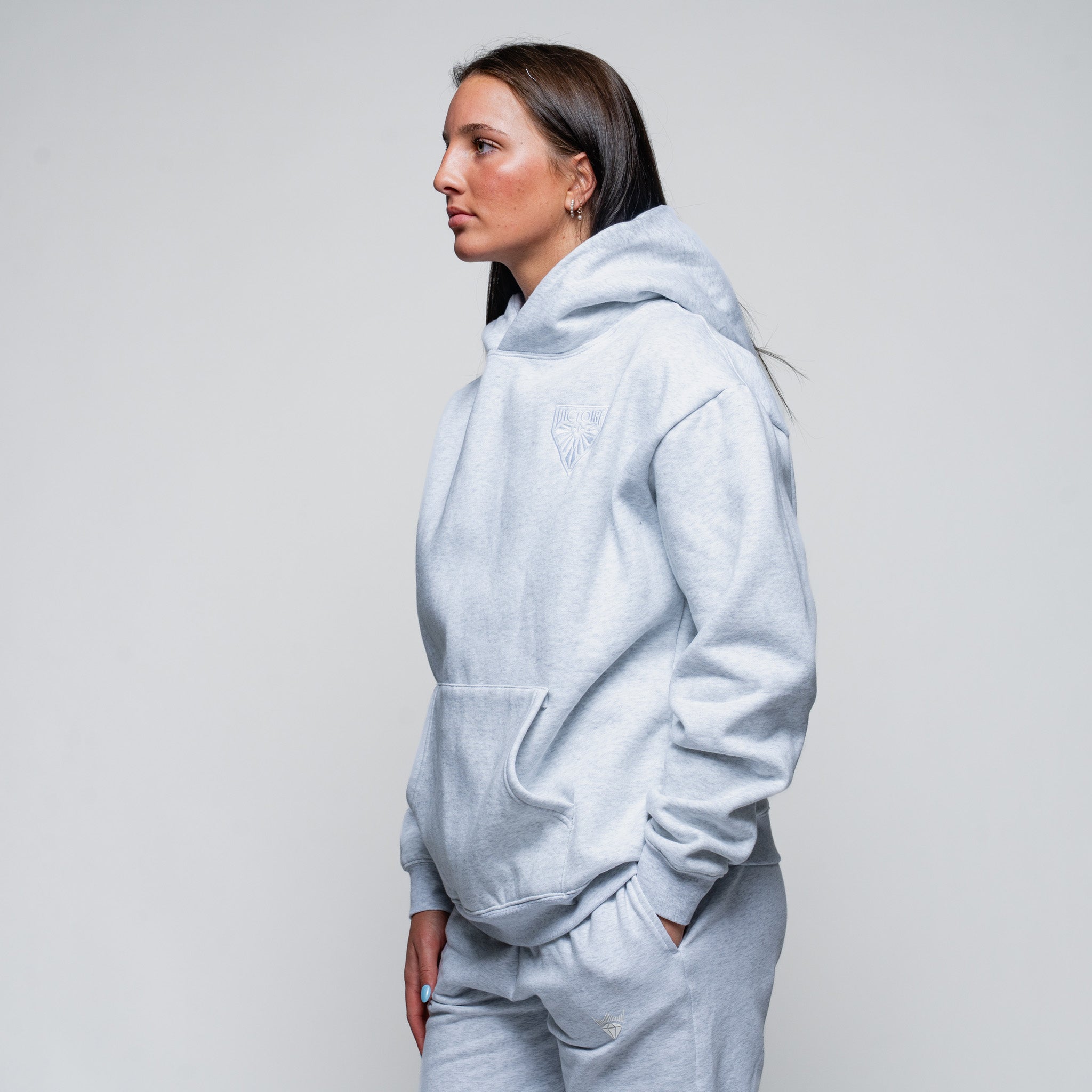 Person wearing a light gray hoodie and pants on a plain background