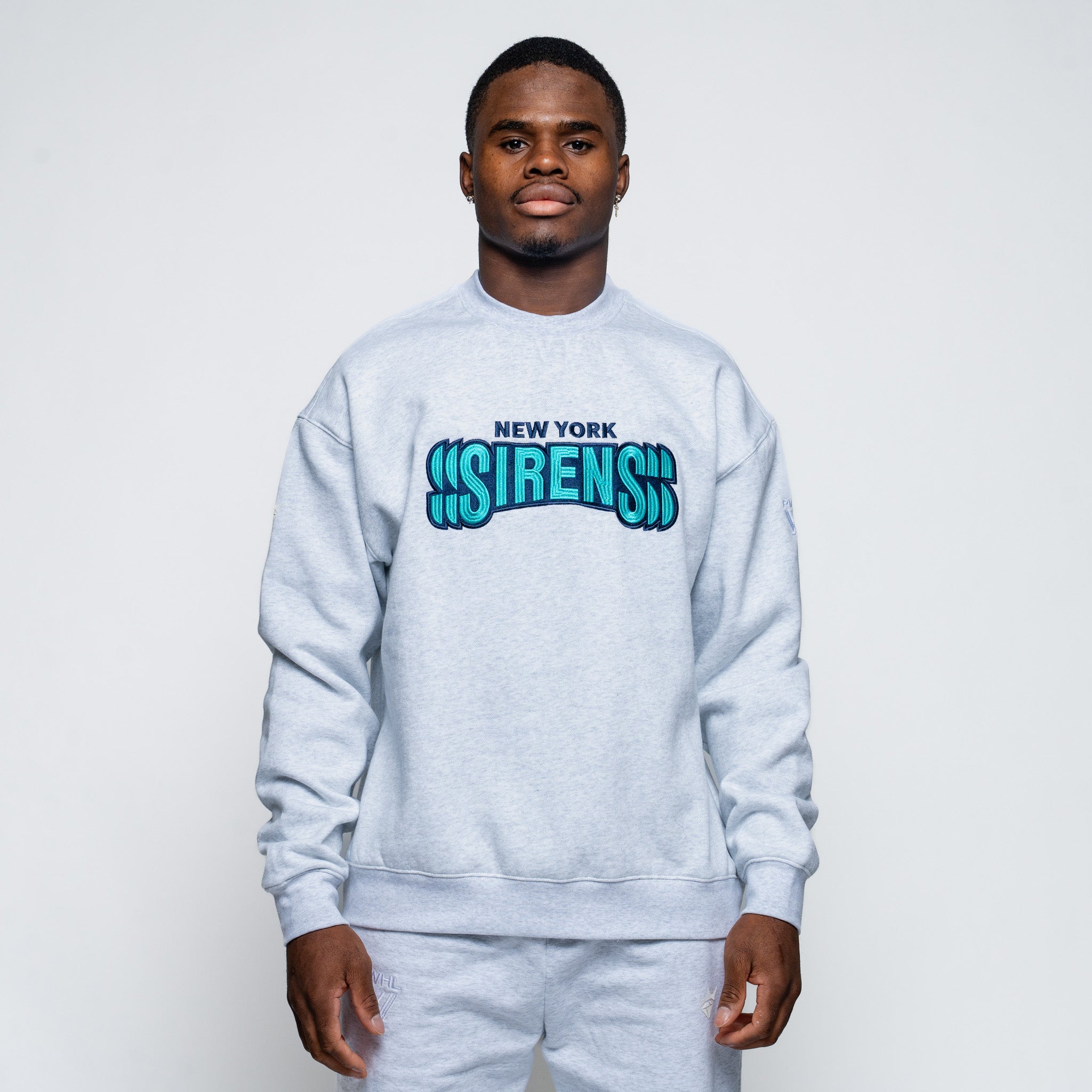 Person wearing a gray sweatshirt with 'New York Sirens' text on a white background