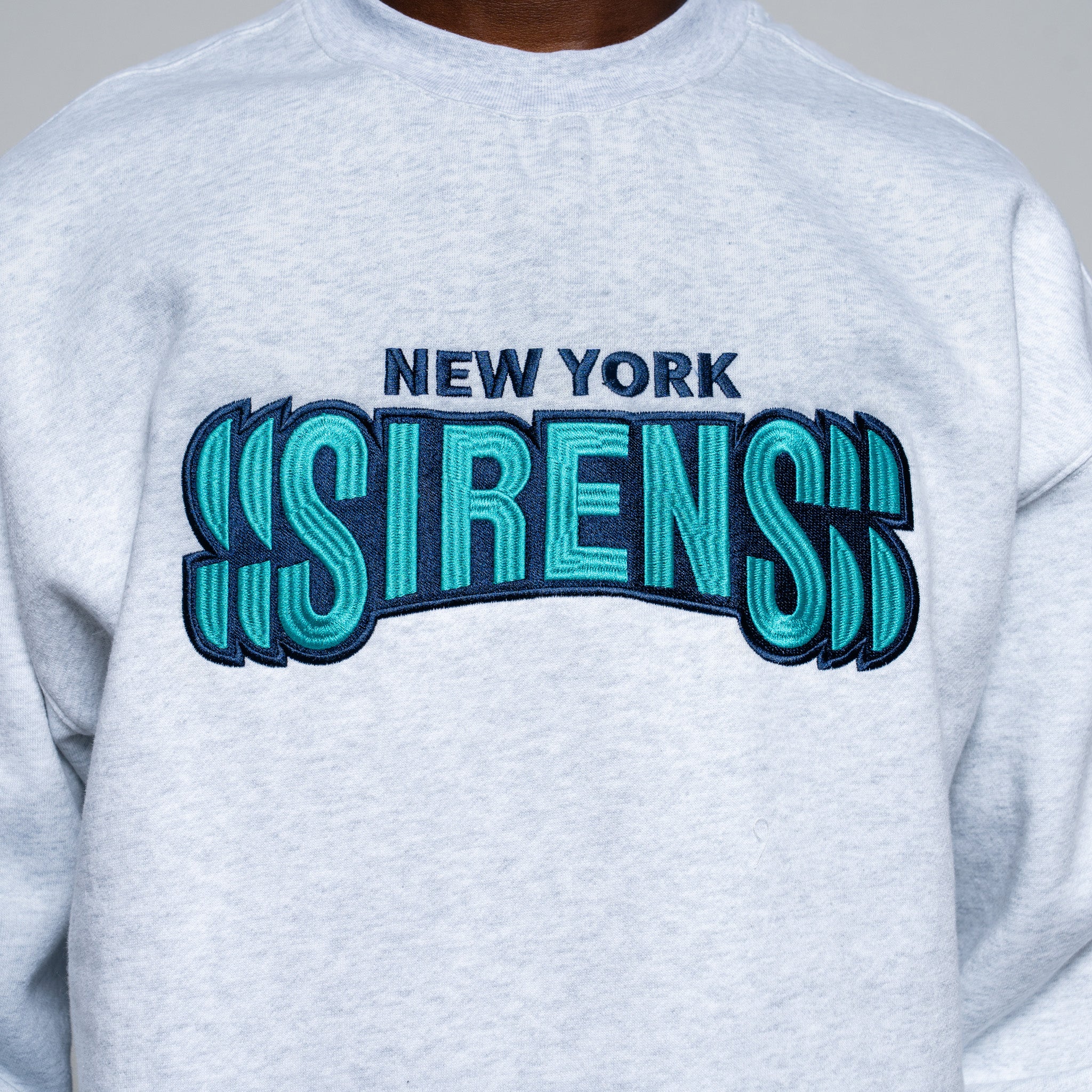 Gray sweatshirt with 'New York Sirens' text in blue and green on a gray background