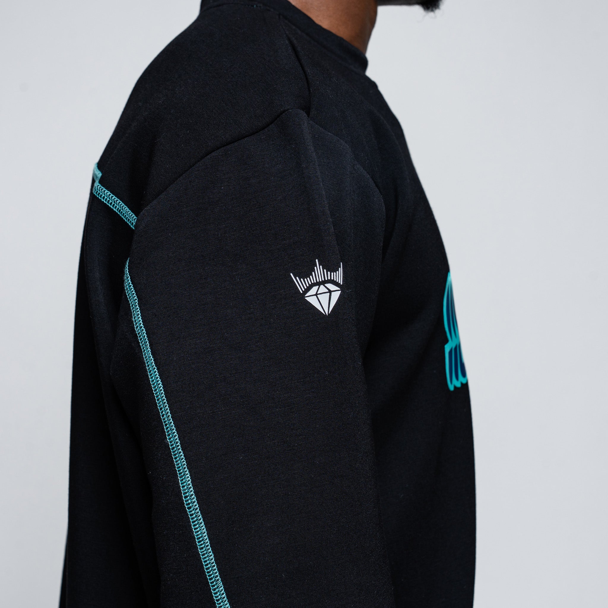 Black sweater with teal accents and a logo on the chest against a white background