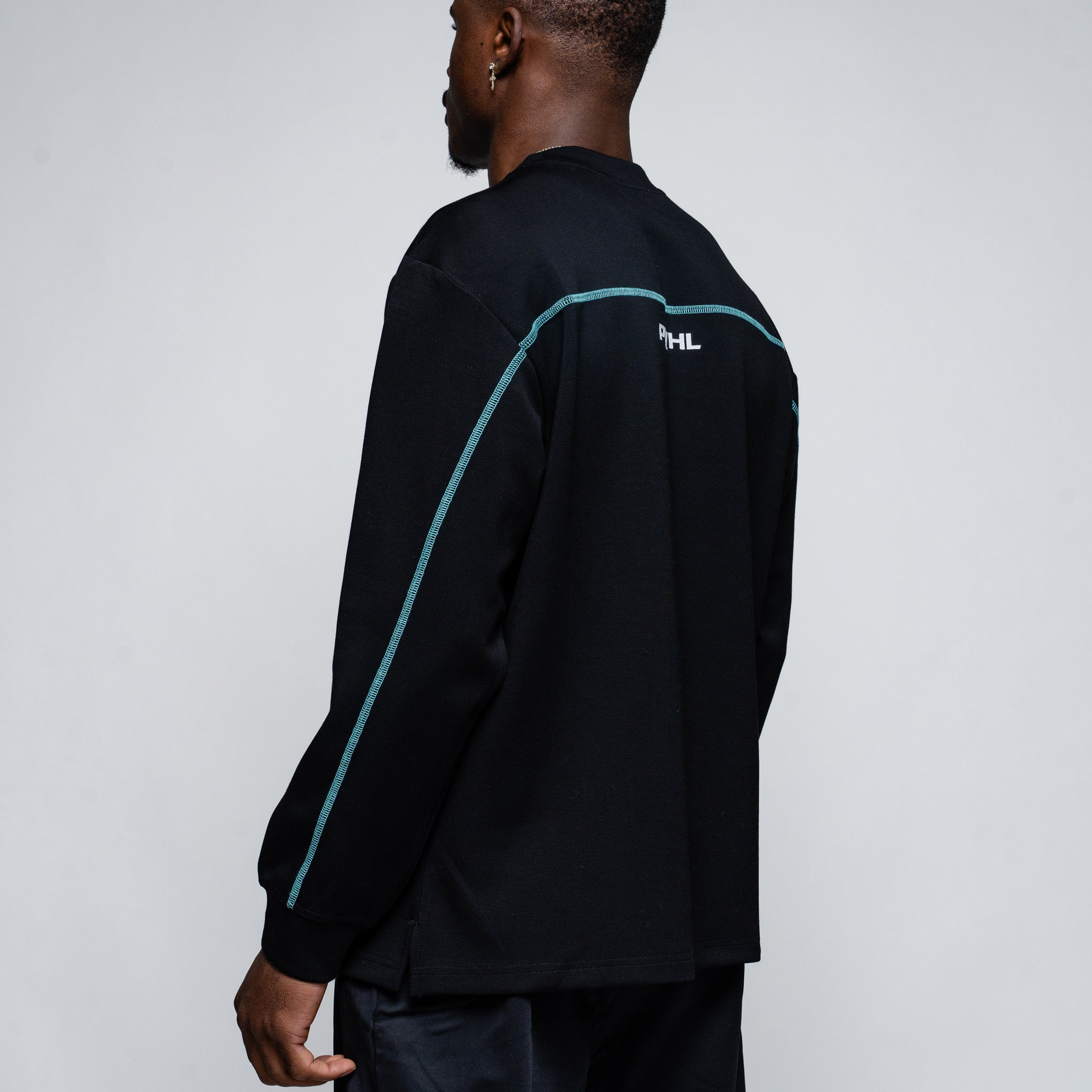 Person wearing a black long-sleeve shirt with blue accents on a plain background