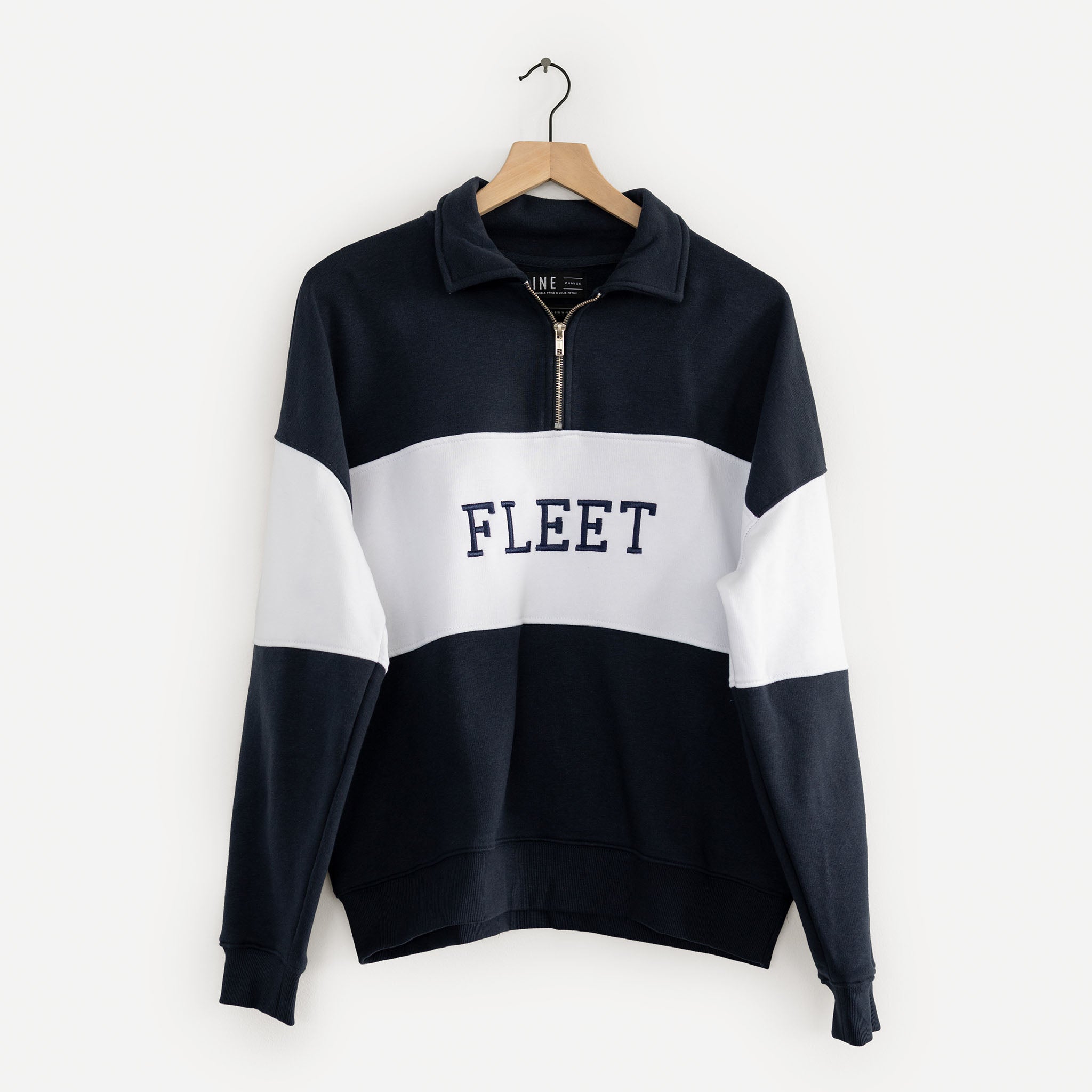 Navy and white sweater with 'FLEET' text on a hanger against a white background