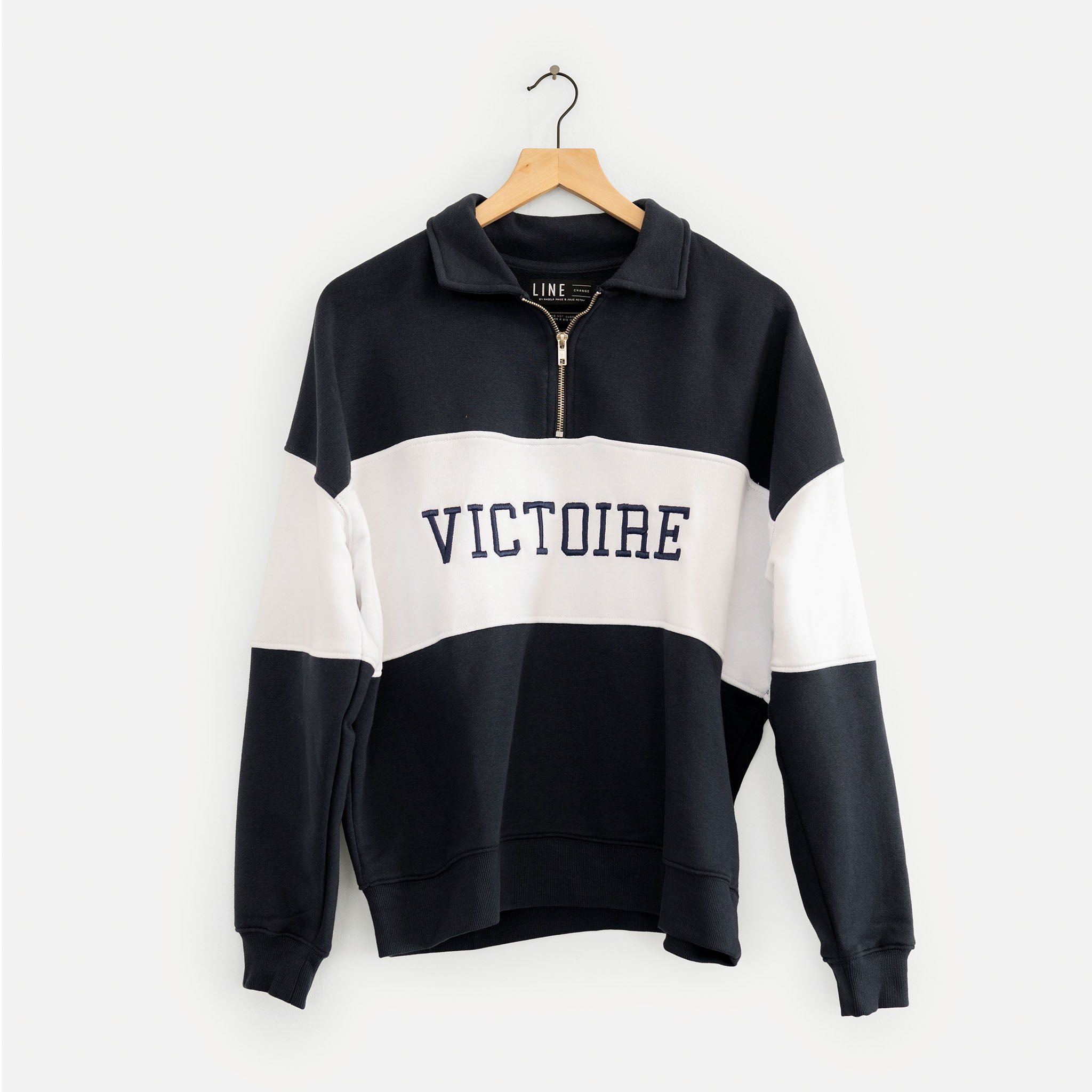 Navy and white striped sweater with 'VICTOIRE' text on a hanger against a white background