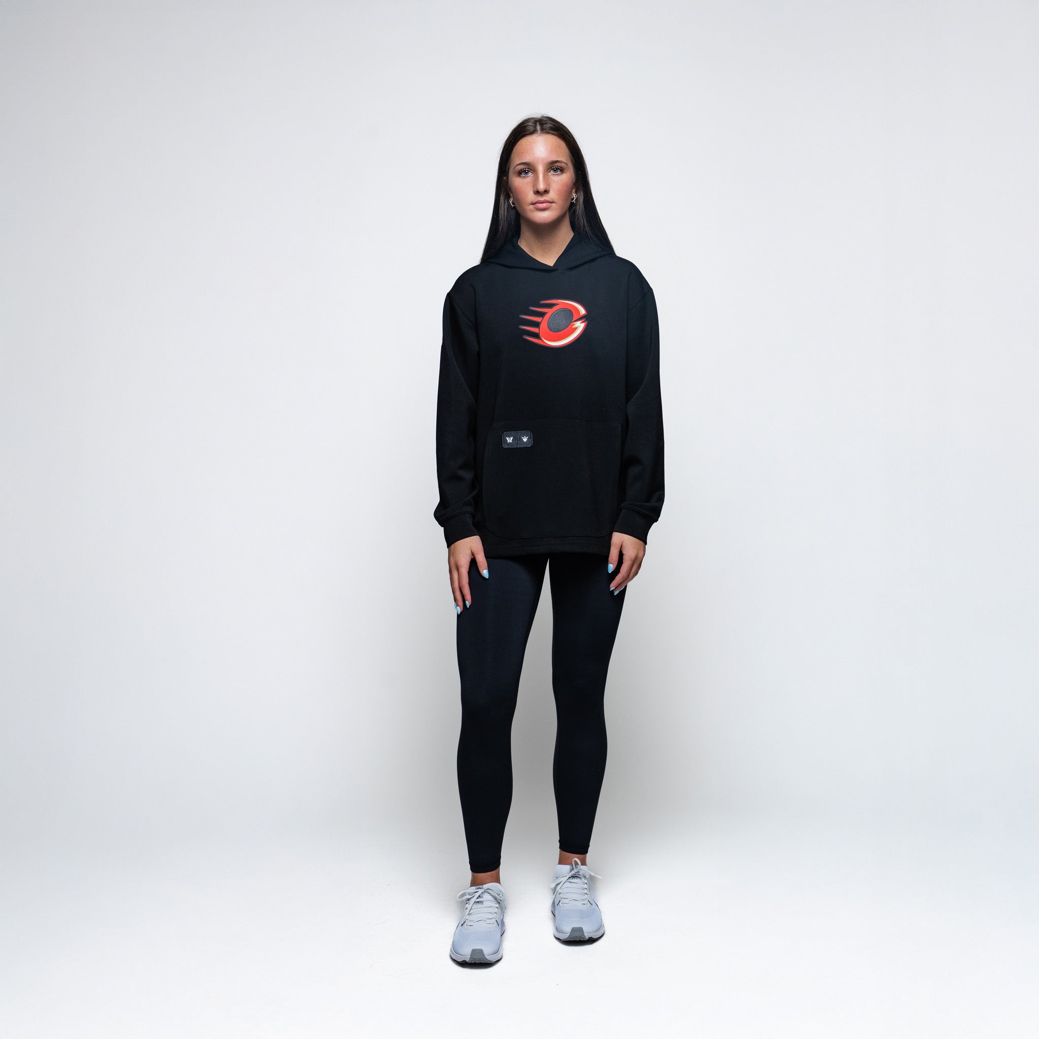 Person wearing a black hoodie with a red logo and black leggings on a white background