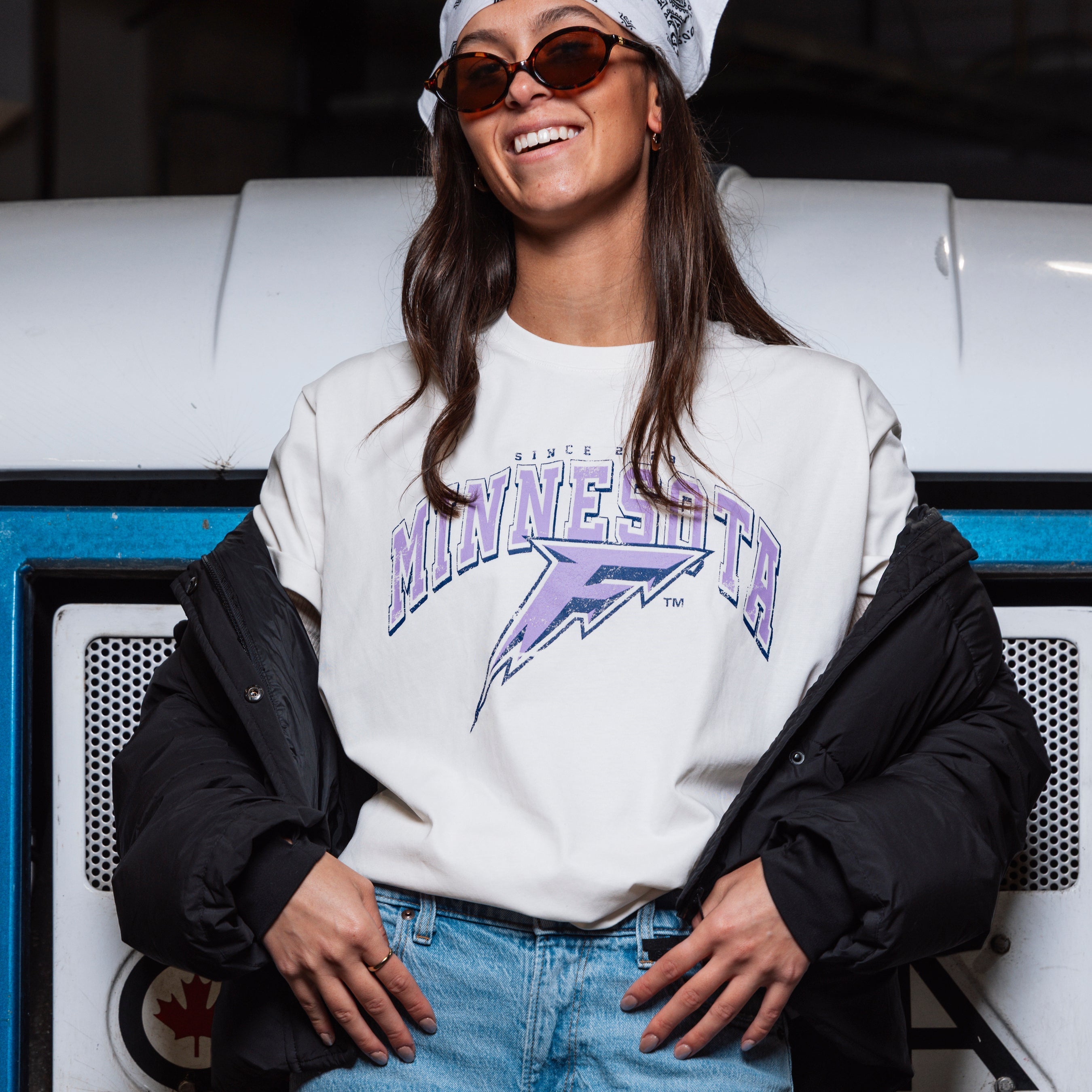 Person wearing a 'Minnesota' sweatshirt sitting on a vehicle.