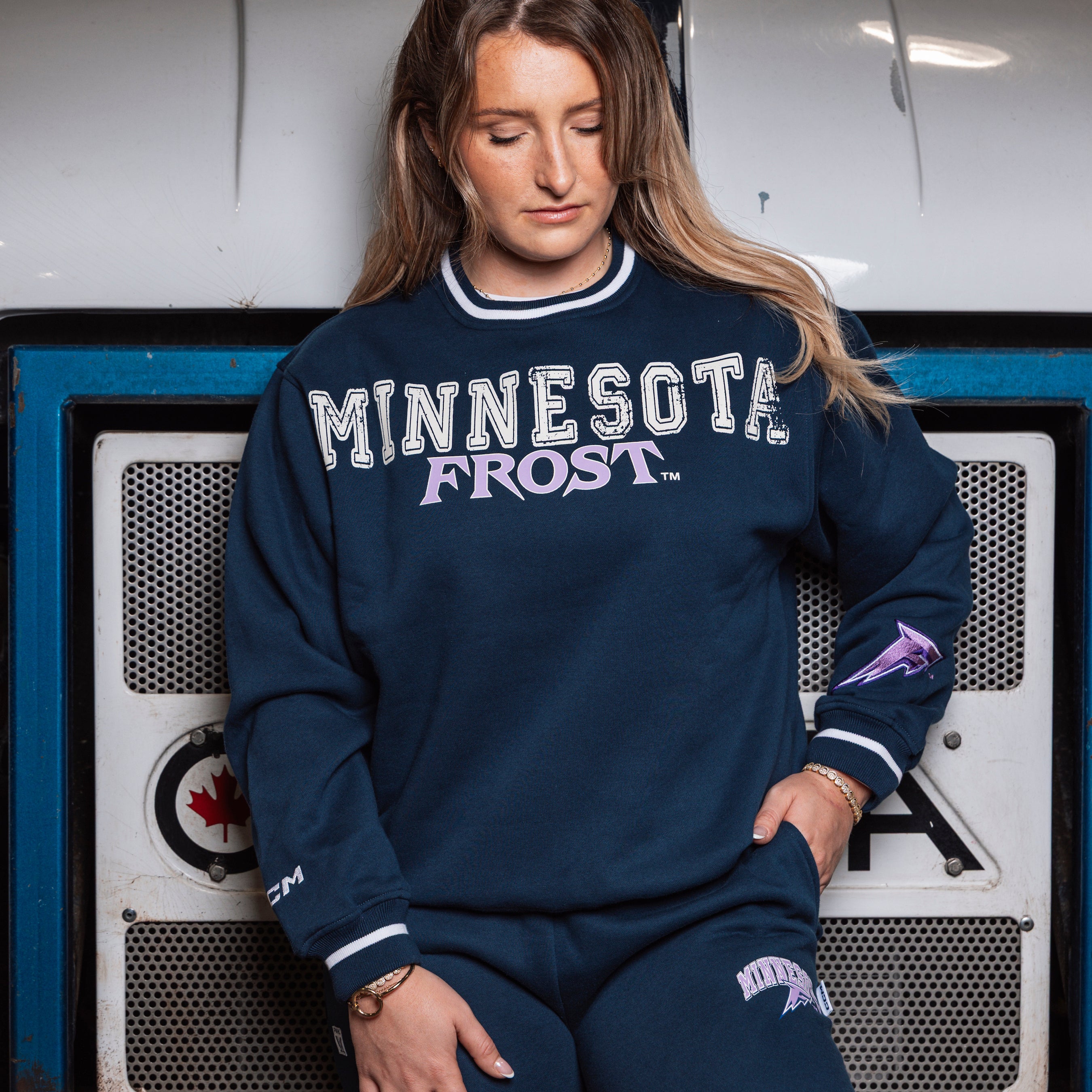 Person wearing a navy 'Minnesota Frost' sweatshirt sitting in front of a vintage appliance.