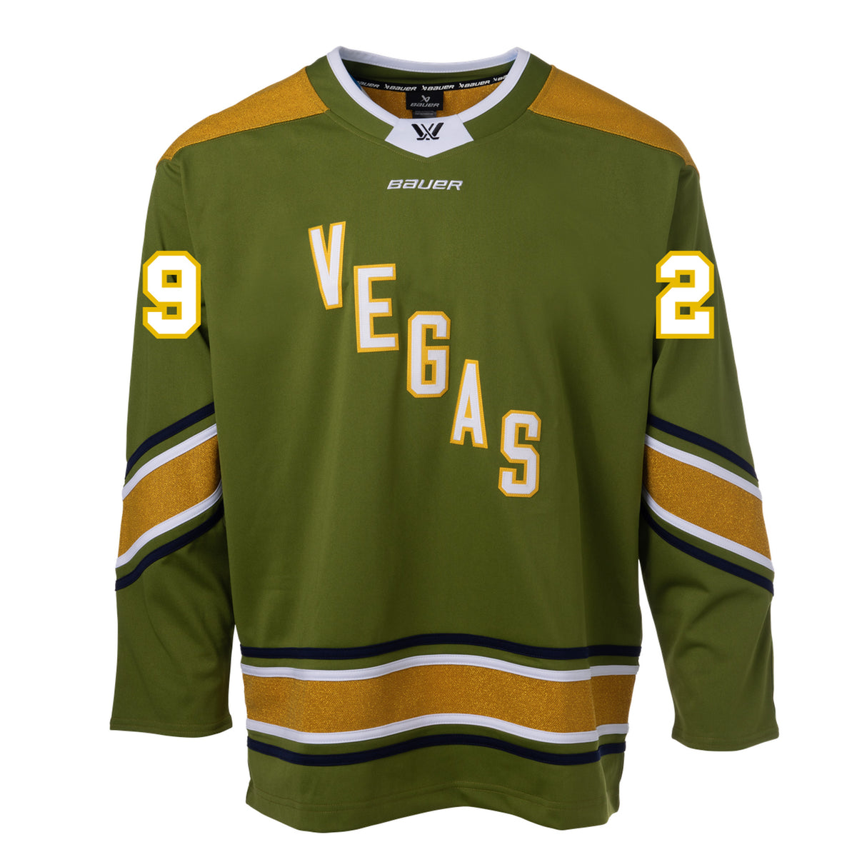 Front of a green jersey with sparkling gold shoulder caps and stripes along the sleeves and bottom hem surrounded by white and black stripes. In white outlined in gold reads 'VEGAS' diagonally across the chest and '29' on each sleeve. The collar is green with white trim on top. A black PWHL logo is centered on the collar with a white BAUER logo below it.
