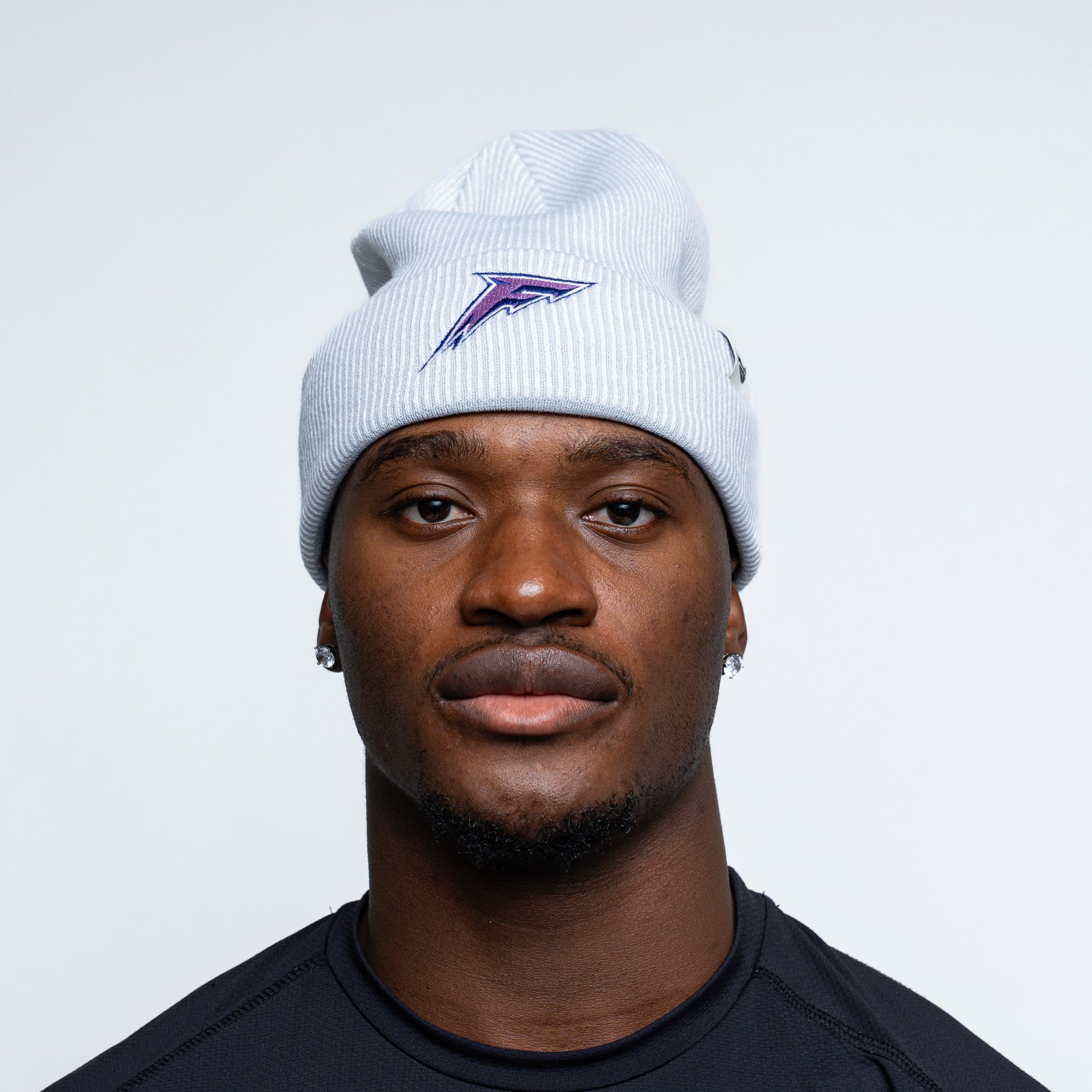 Person wearing a white beanie with a logo on a plain background