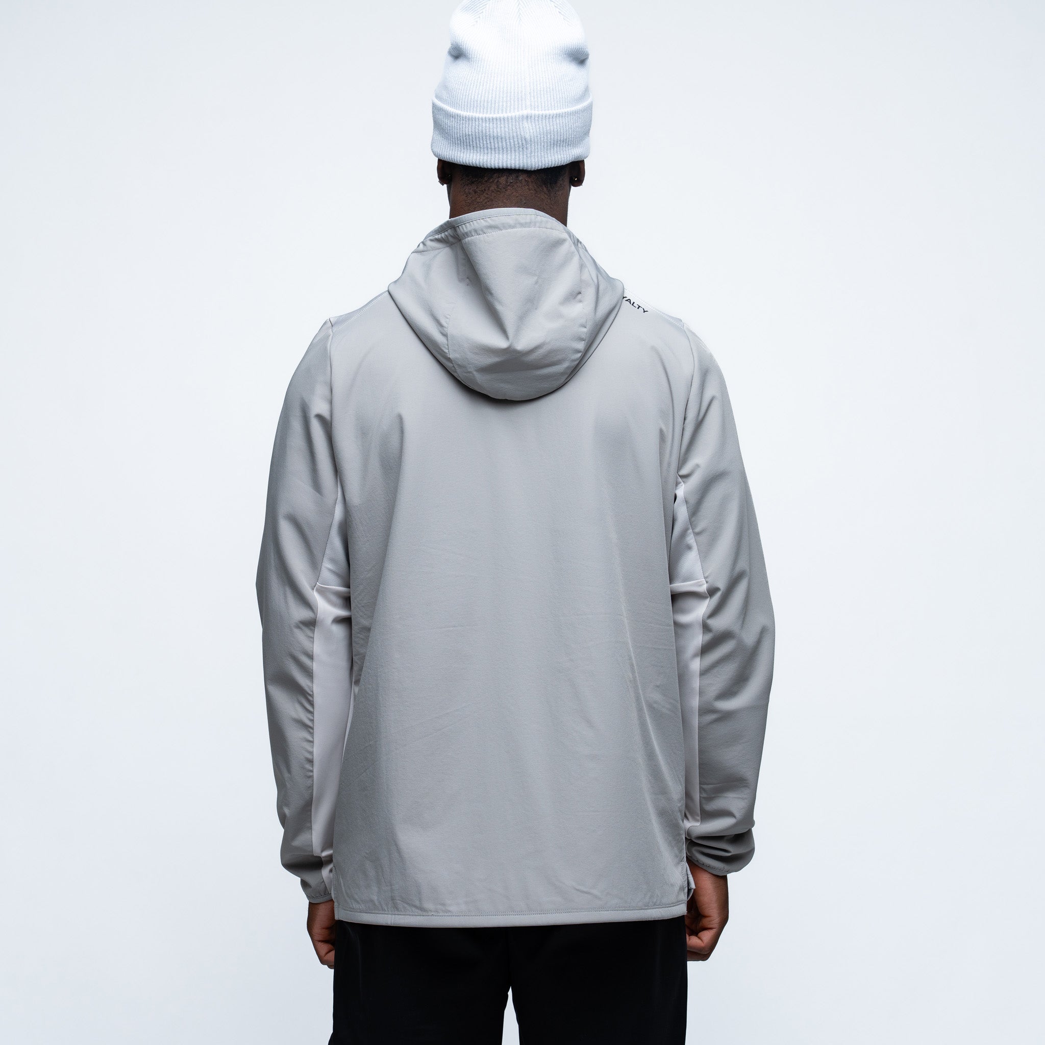 Person wearing a gray jacket and white beanie from behind on a light gray background