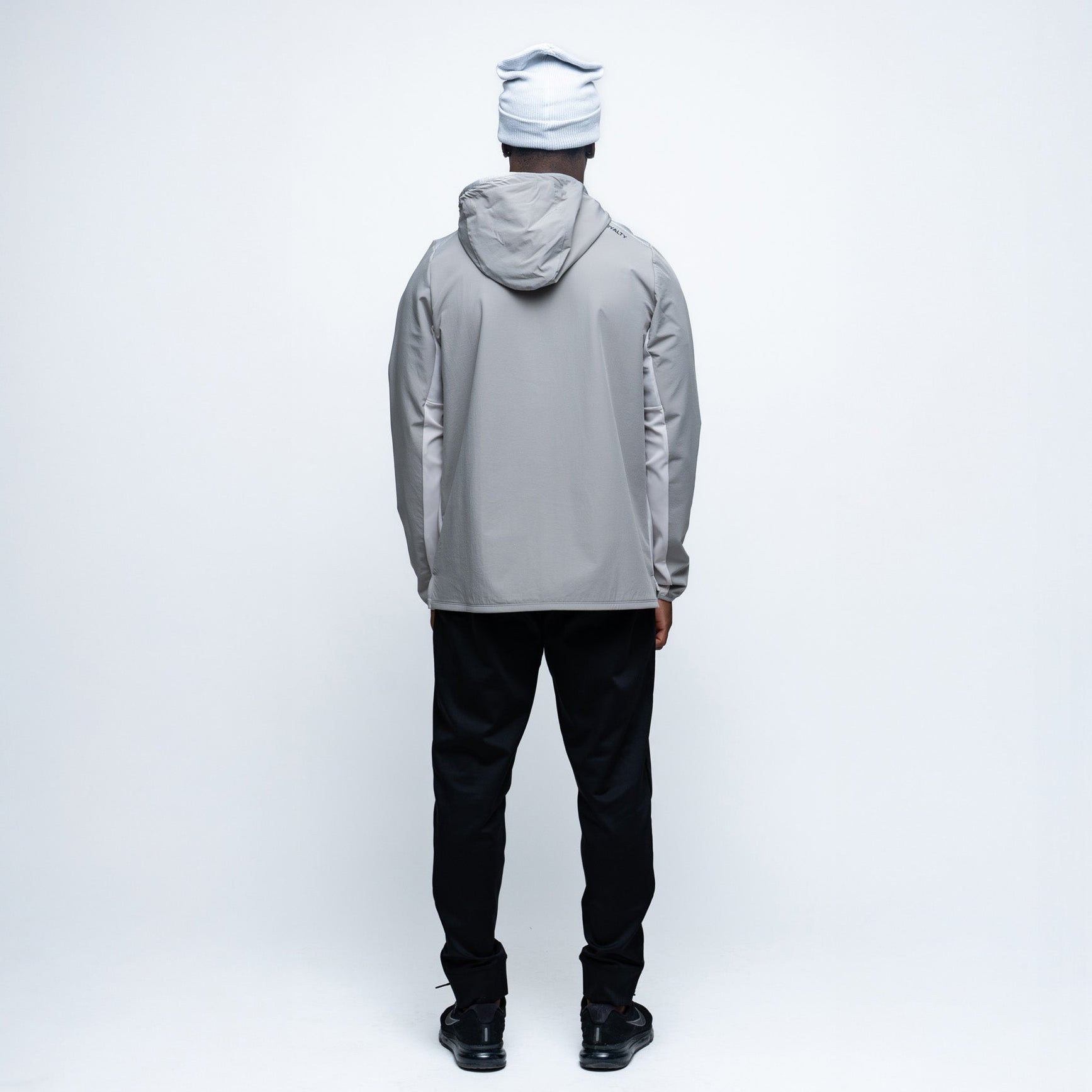 Person wearing a gray jacket and black pants on a white background