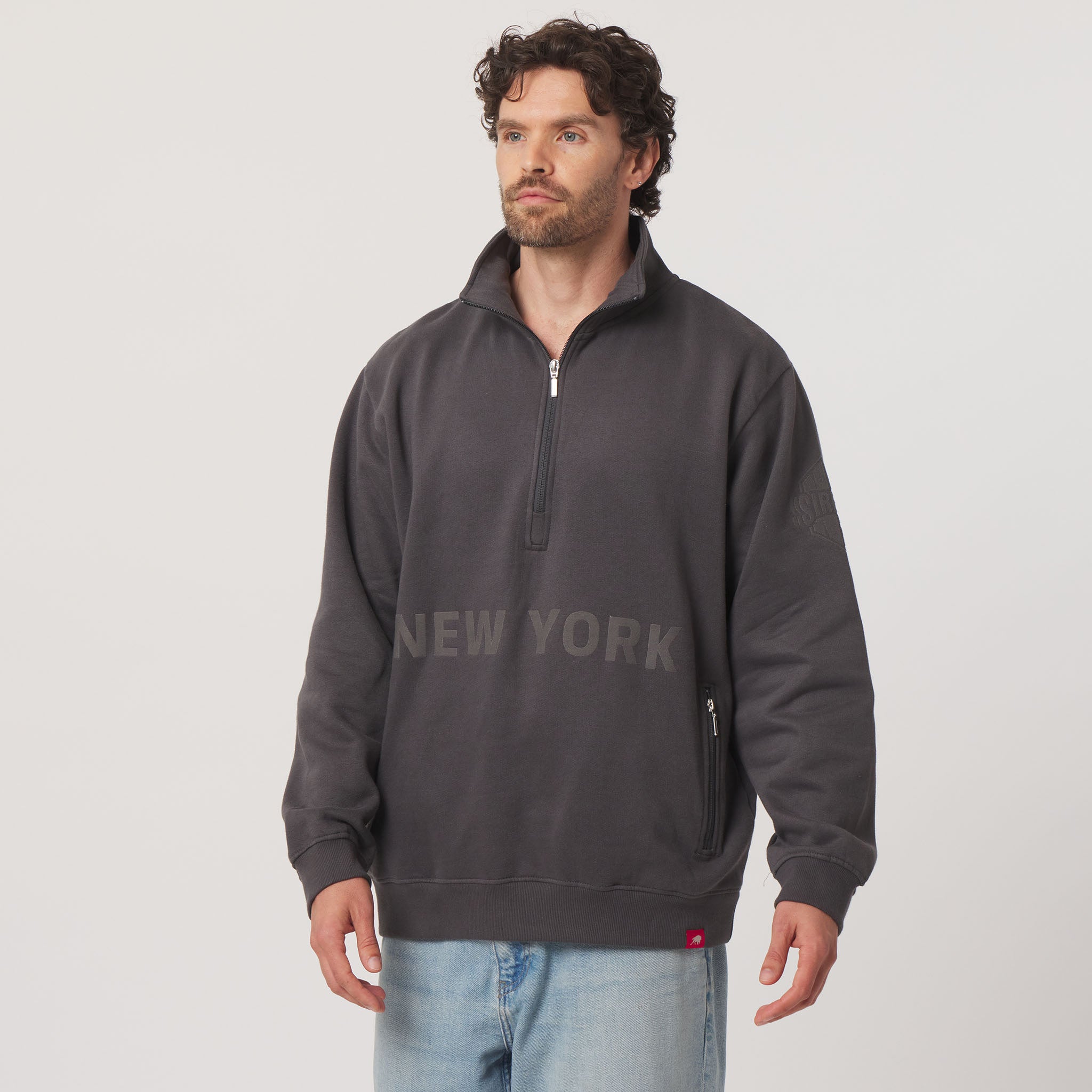 Man wearing a dark gray 'New York' sweatshirt on a light gray background