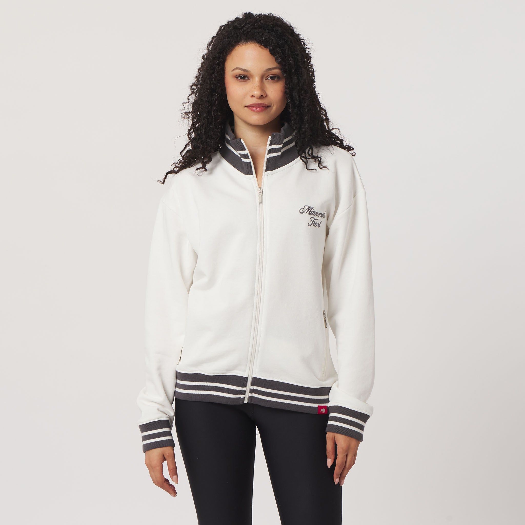 Woman wearing a white jacket with black accents on a plain background