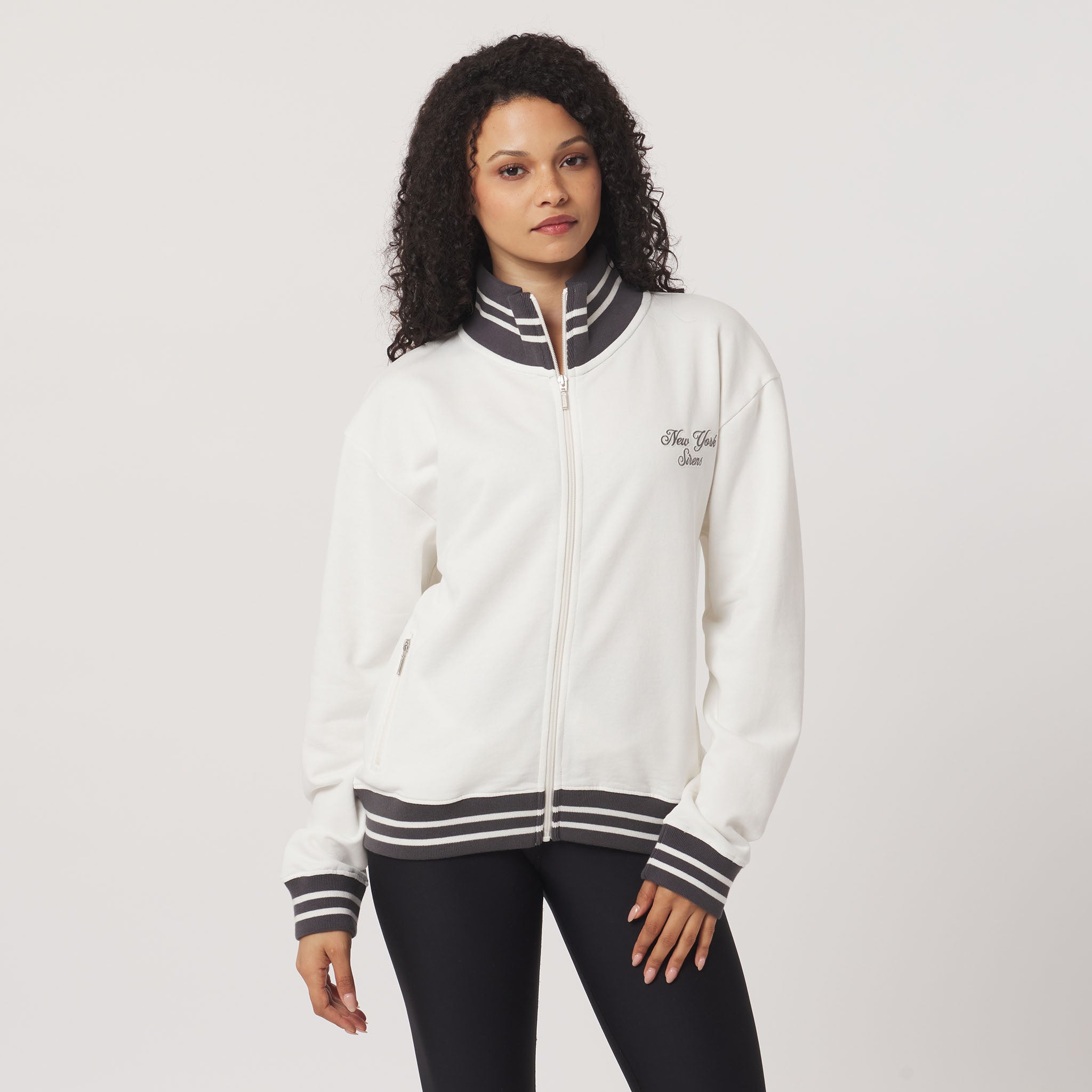 Woman wearing a white jacket with black and gray accents on a plain background