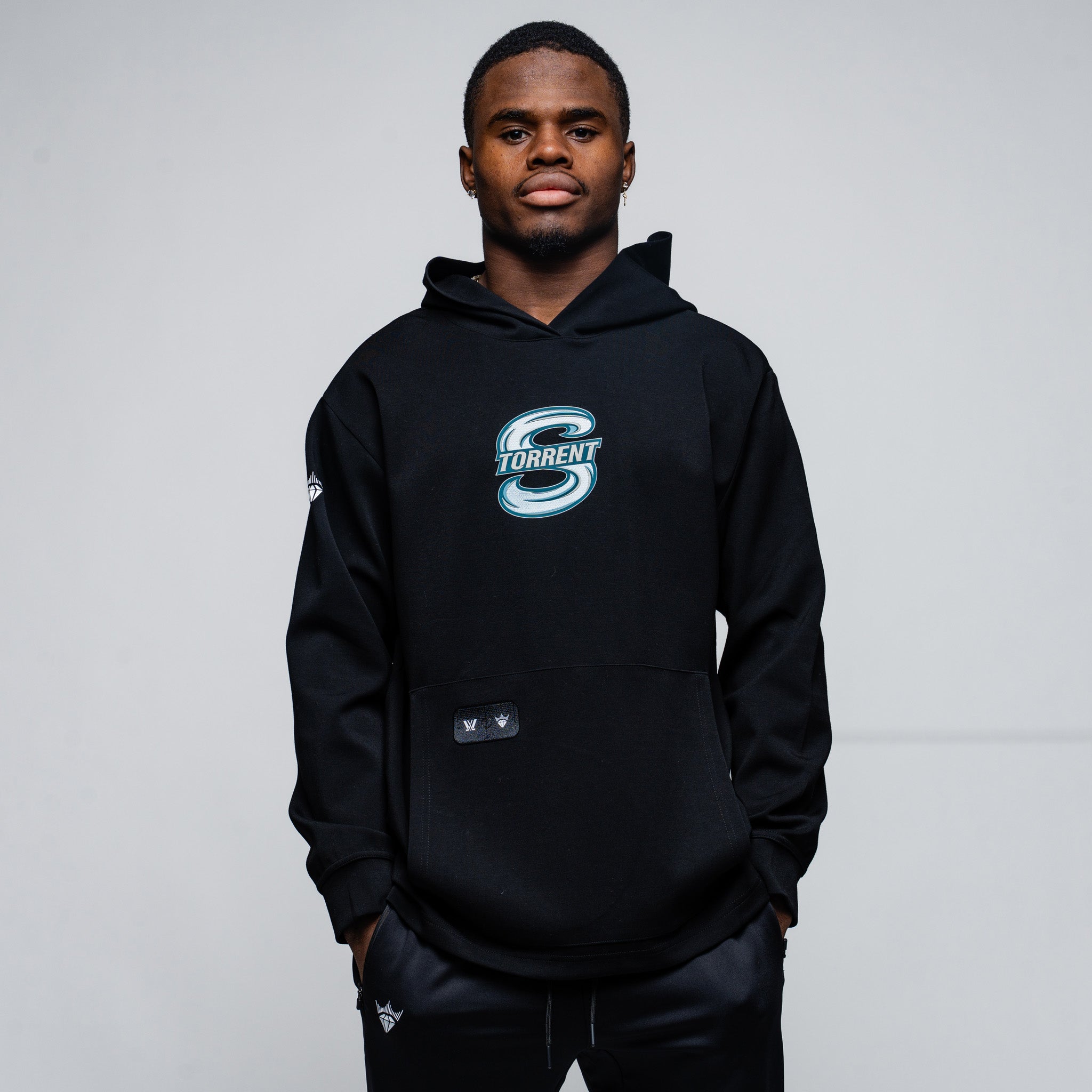 Person wearing a black hoodie with a logo on a gray background